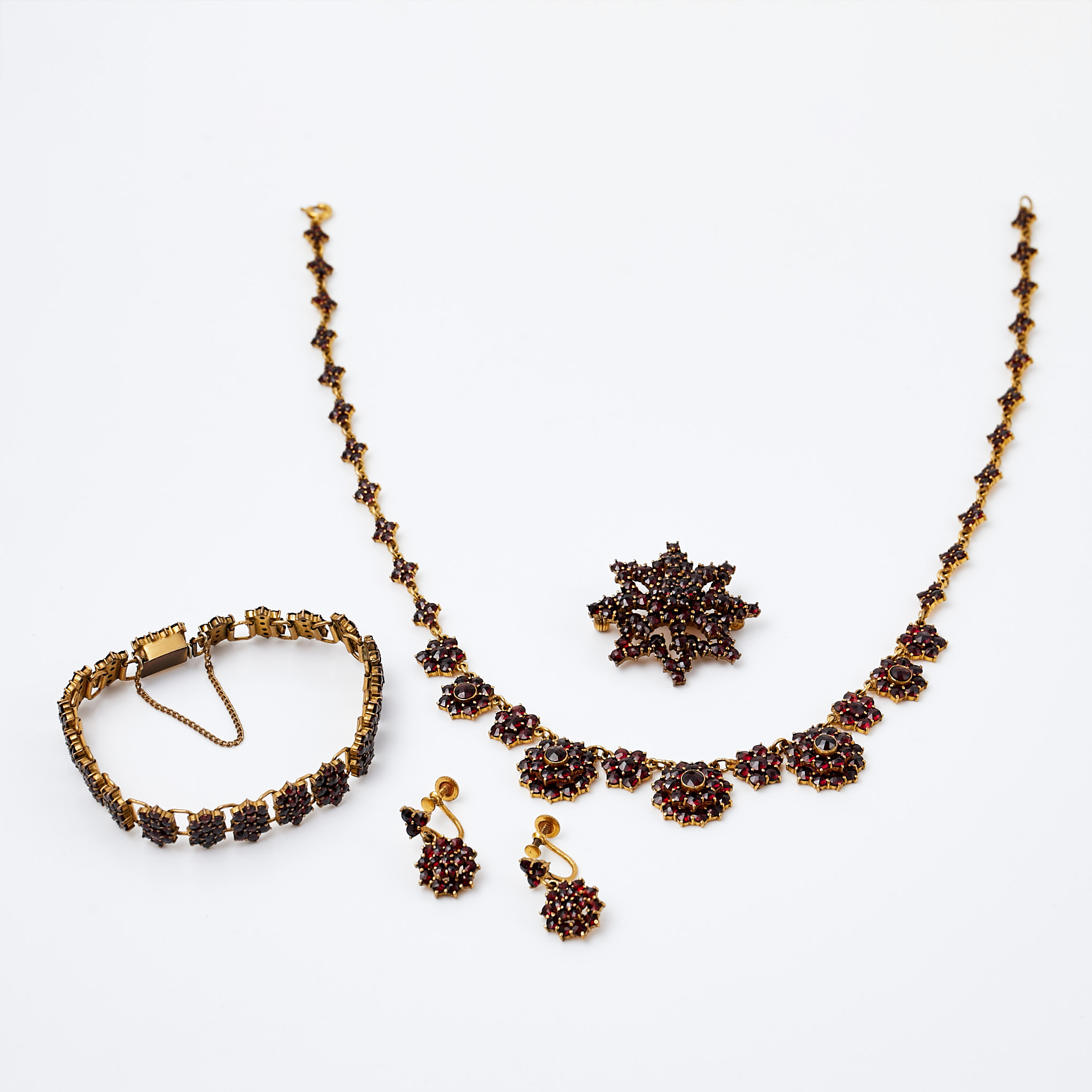 COLLIER, ARMBAND, BROSCH samt ÖRHÄNGEN, 1 par, 1900-talets mitt, mässing, med dekor av granater, utländska stämplar, med skruvmekanism.