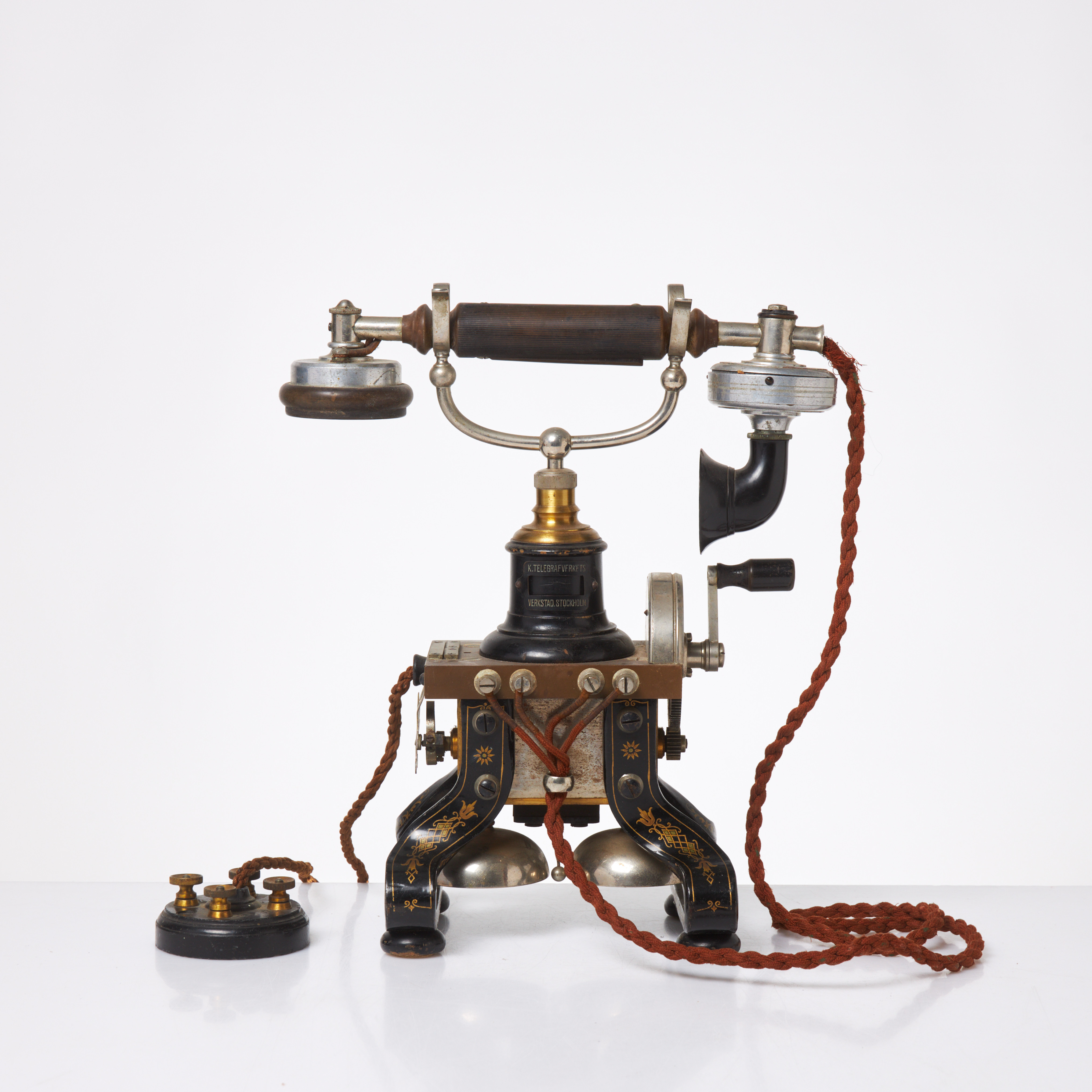 BORDSTELEFON, LM Ericsson, modell 1892, även kallad Taxen, svartlackerat järn med förnicklade och litograferade detaljer, flätad textilsladd, för lokalbatteri, med separat handmikrotelefon, hörlur samt taltratt i bakelit.