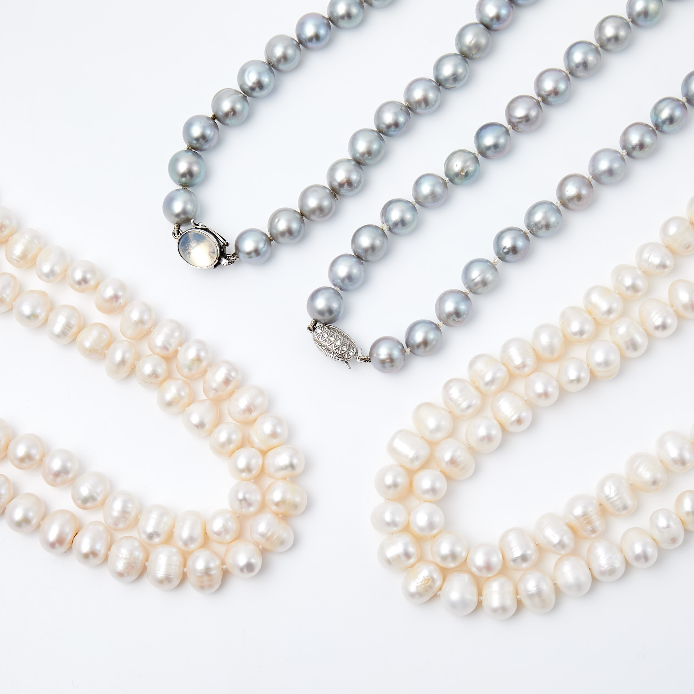 HALSBAND, 4 st, odlade vita samt grå sötvattenspärlor, lås i sterlingsilver med månsten resp. strass, svensk importstämpel samt tyska stämplar.
