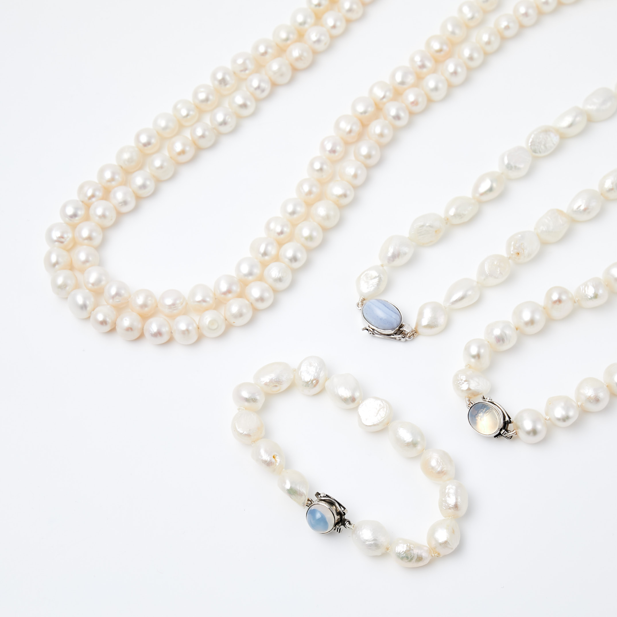 HALSBAND, 3 st, ARMBAND, ÖRHÄNGEN, 1 par, odlade vita sötvattenspärlor, lås i silver med månsten resp. agat, bl.a. med svensk importstämpel.