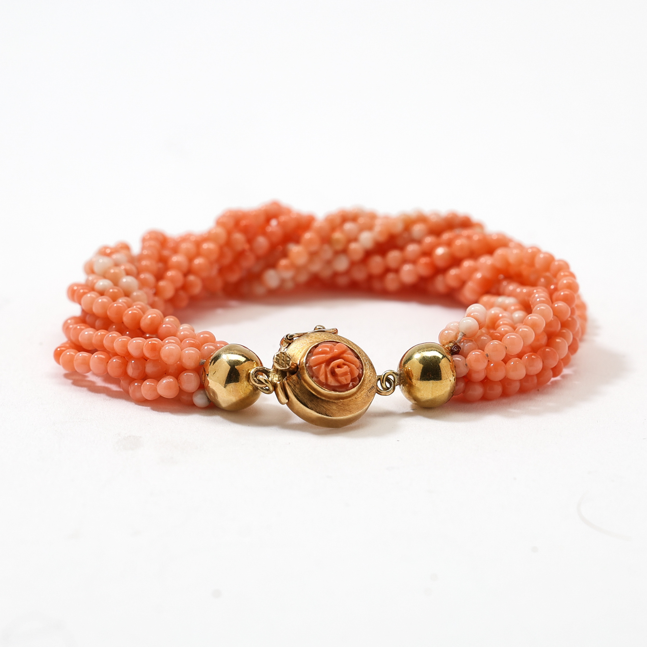 ARMBAND, tioradigt med korallkulor med lås i 18K guld.