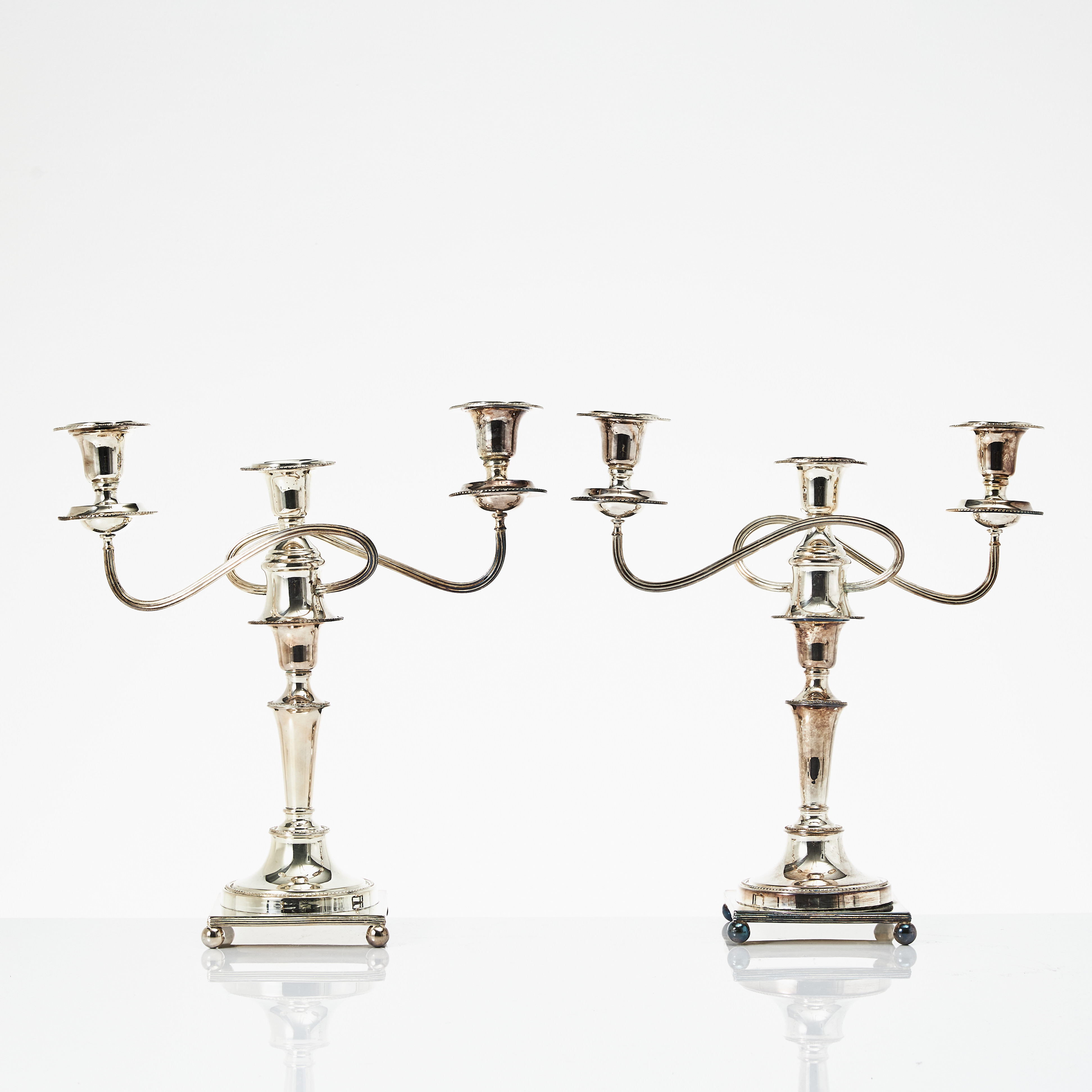 KANDELABRAR, ett par, nysilver, England, 1900-talets mitt, för tre ljus, kvadratisk fotplatta med kulfötter, konverteringsbara.