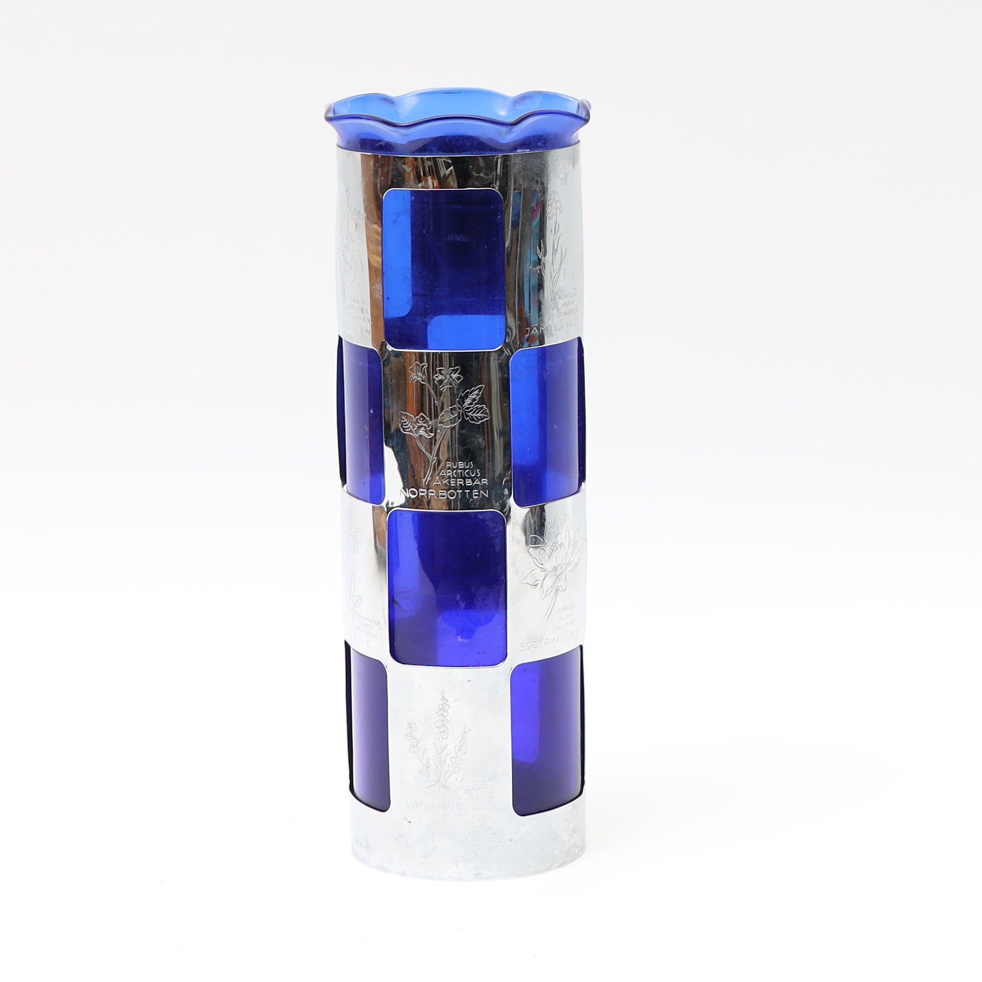 VAS, blåtonat glas med ytterhölje av förnicklad metall. Graverad dekor med landskapsblommor.