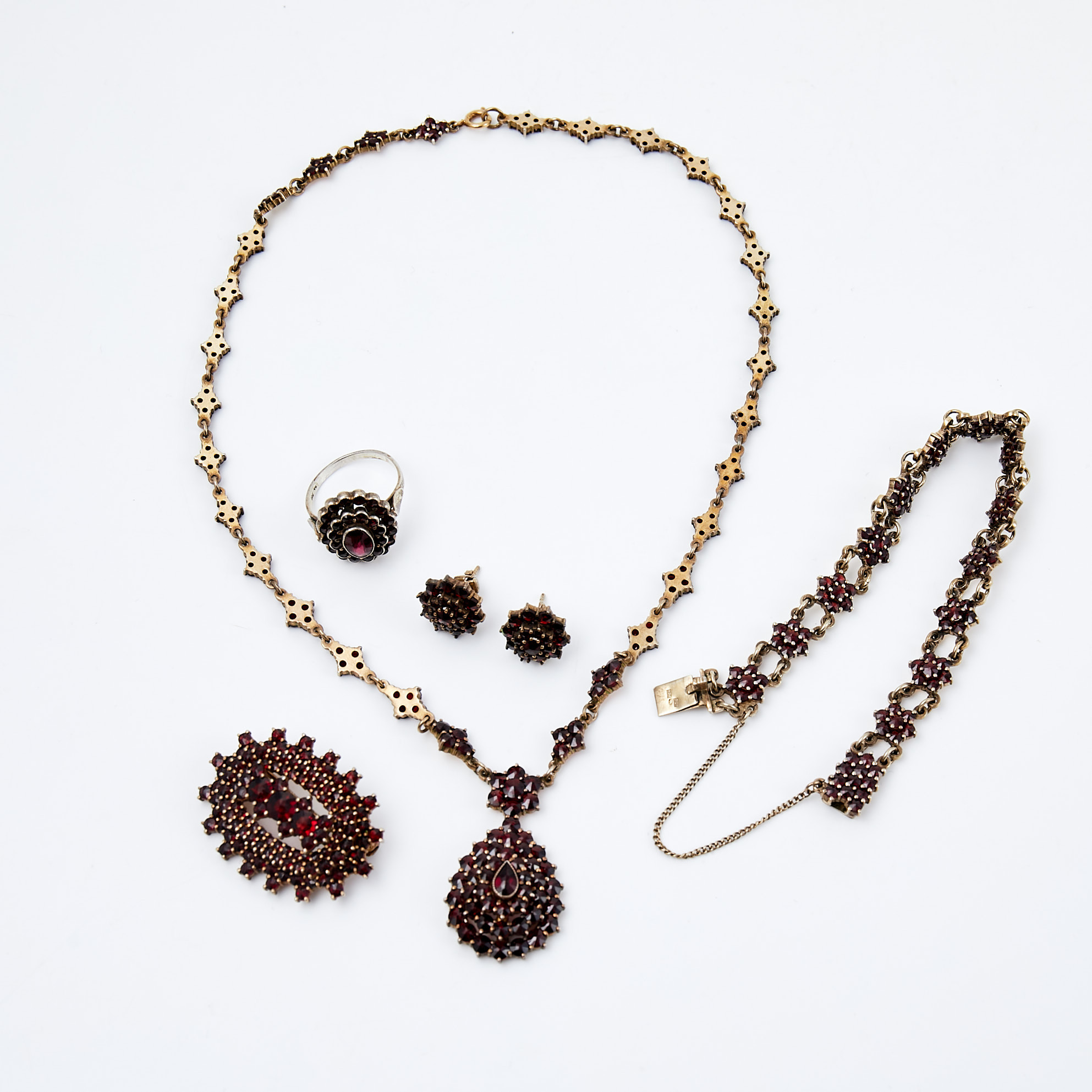 GARNITYRSET, 5 dlr, silver, delvis förgyllt, med fasettslipade granater, olika tillverkare, bl.a. Hugo Grün, Helsingfors, 1900-tal, i etui.