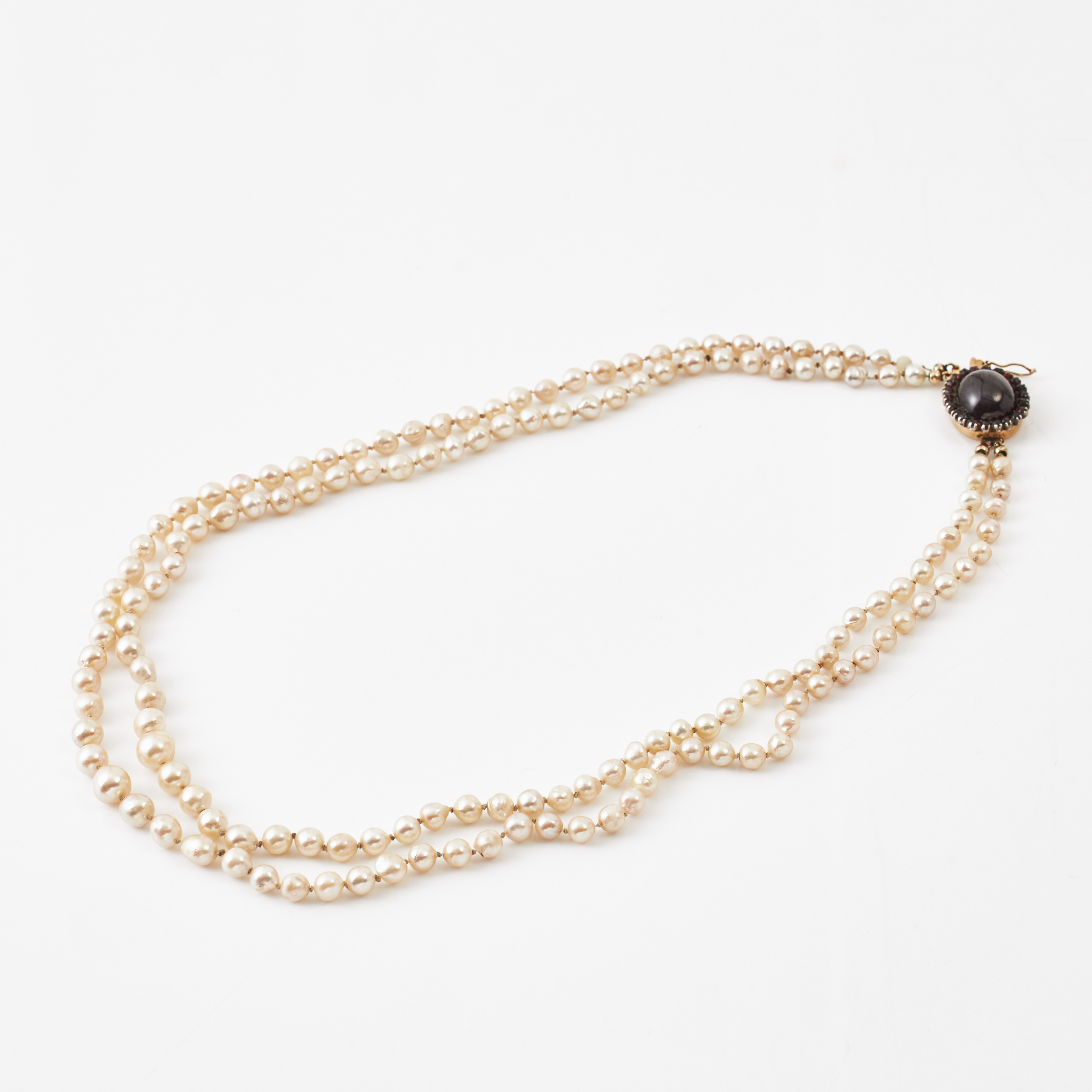 COLLIER, 2-radigt, doserat, odlade barocka saltvattenspärlor ca 3,5-7,8 mm, lås, 18 k guld, dekor med cabochonslipad granat bekransad av små rosenslipade granater i silvermontering.