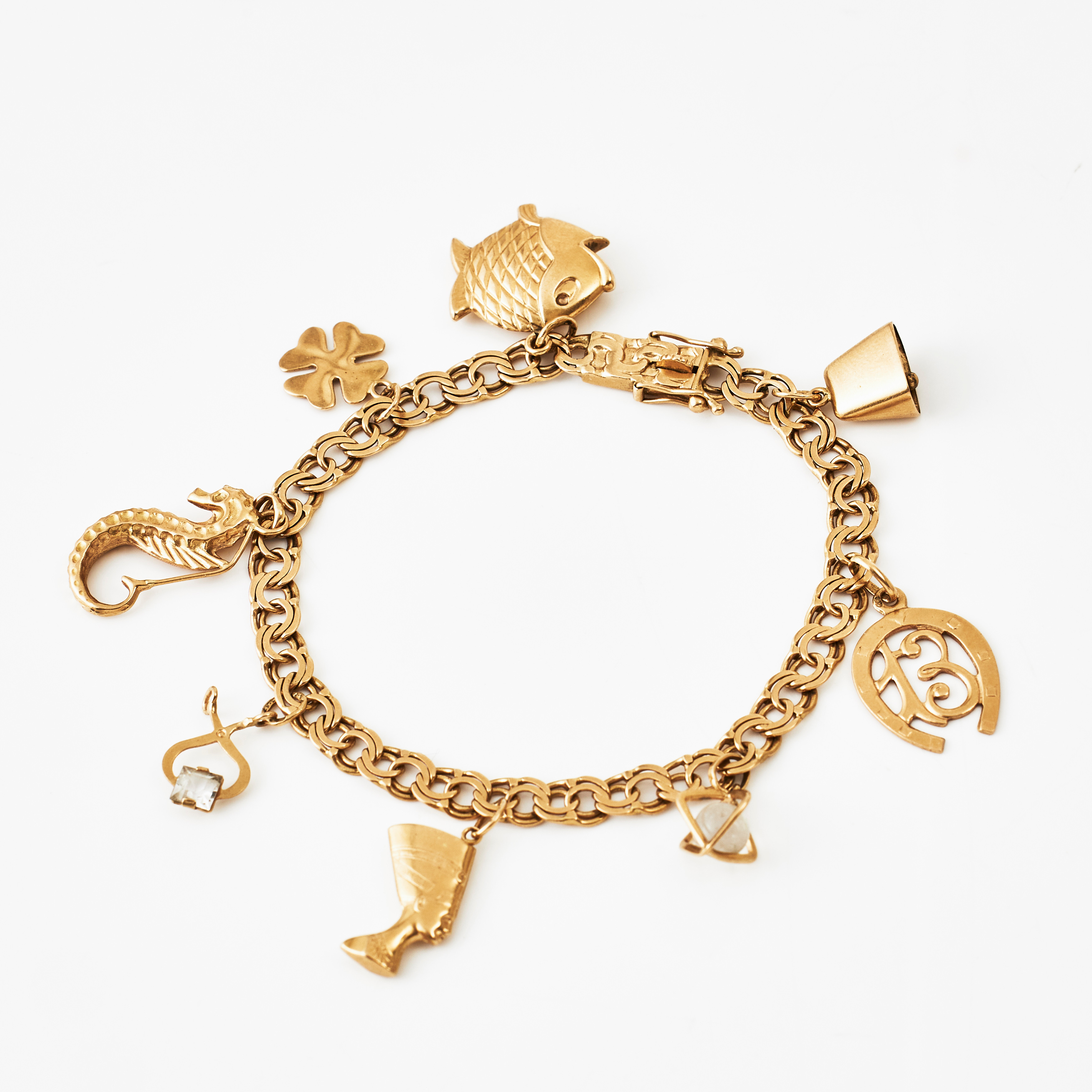 ARMBAND, 18 k guld, Bismarck, med berlocker bl a föreställande Nefertiti, fyrklöver, hästsko med talet 13, koskälla, Gustaf Dahlgren & Co, Malmö 1961.