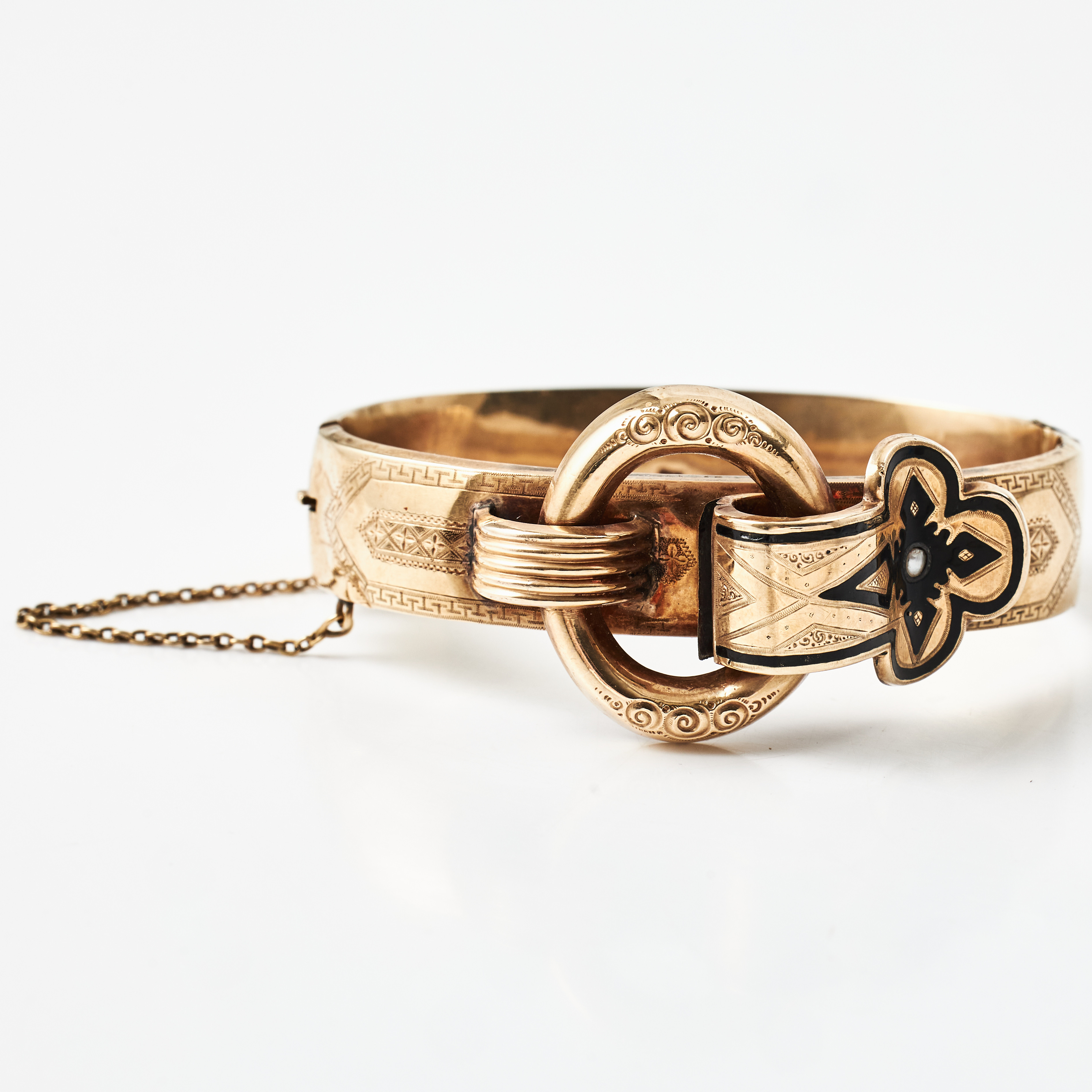 ARMRING, 14 k guld, i form av ett skärpspänne, svart emalj, liten orrientpärla, graverad dekor, utländska stämplar, 1800-talets senare del.