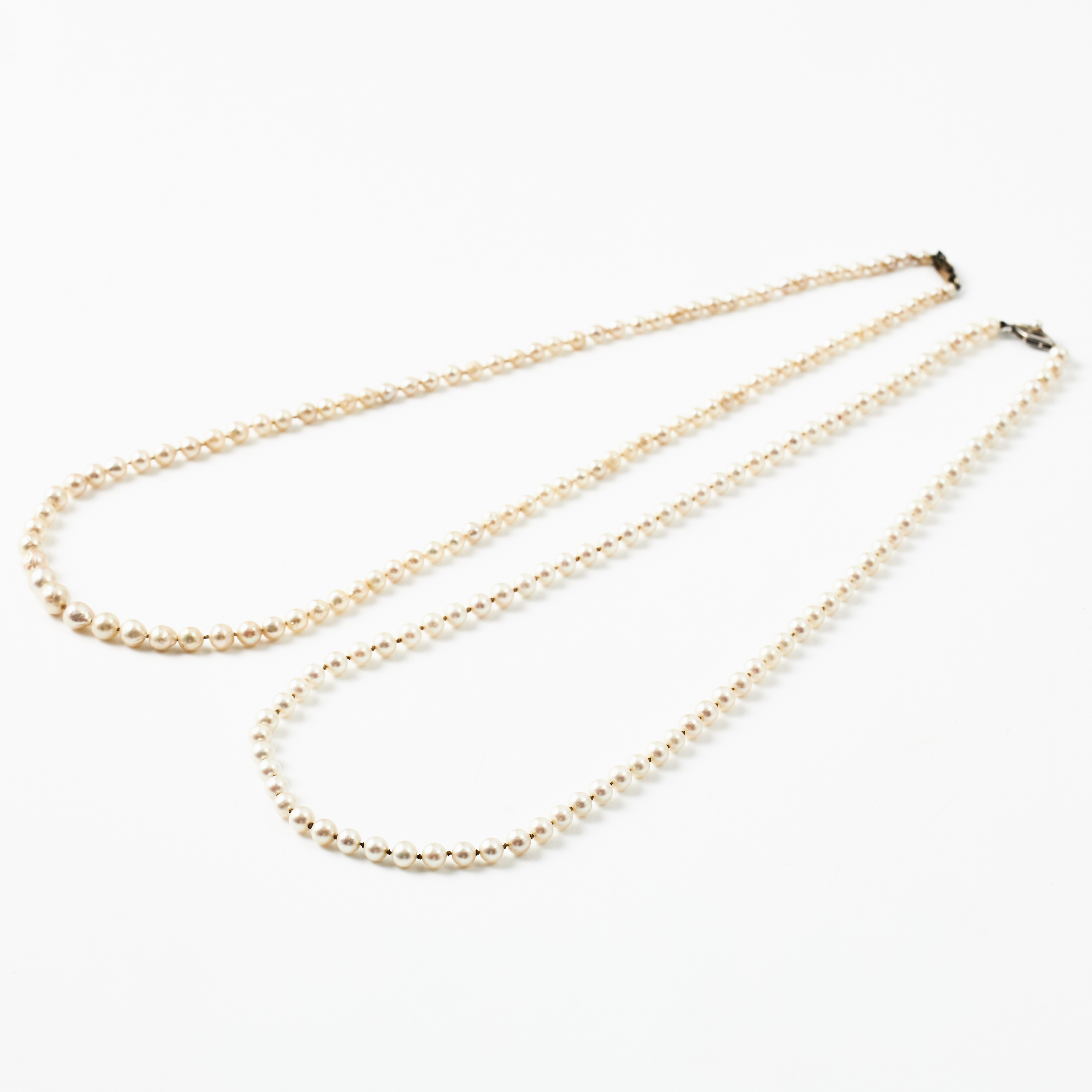 COLLIER, 2 st., odlade saltvattenspärlor ca 3,3-7 mm, ett doserat med barocka pärlor, lås, gulmetall resp. lås, 18 k vitguld.