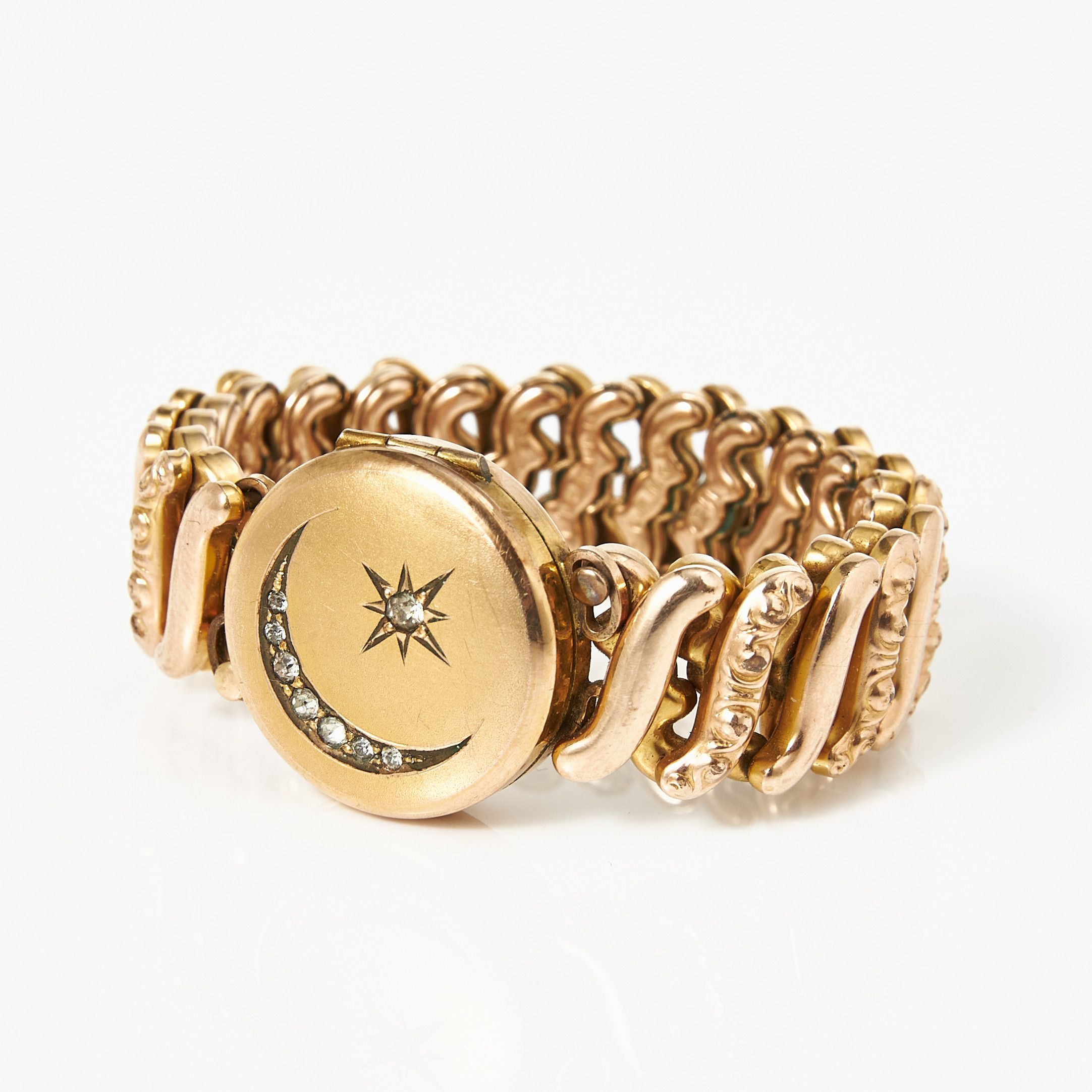 ARMBAND, förgyllt, s.k. "Carmen expansion bracelet", märkt The DFB Co Patented, öppningsbart mittparti, fotogömma, lock med halvmåne och stjärna (Celestials) med dekor av vita fasettslipade pastestenar, omkring 1900-talets första del.