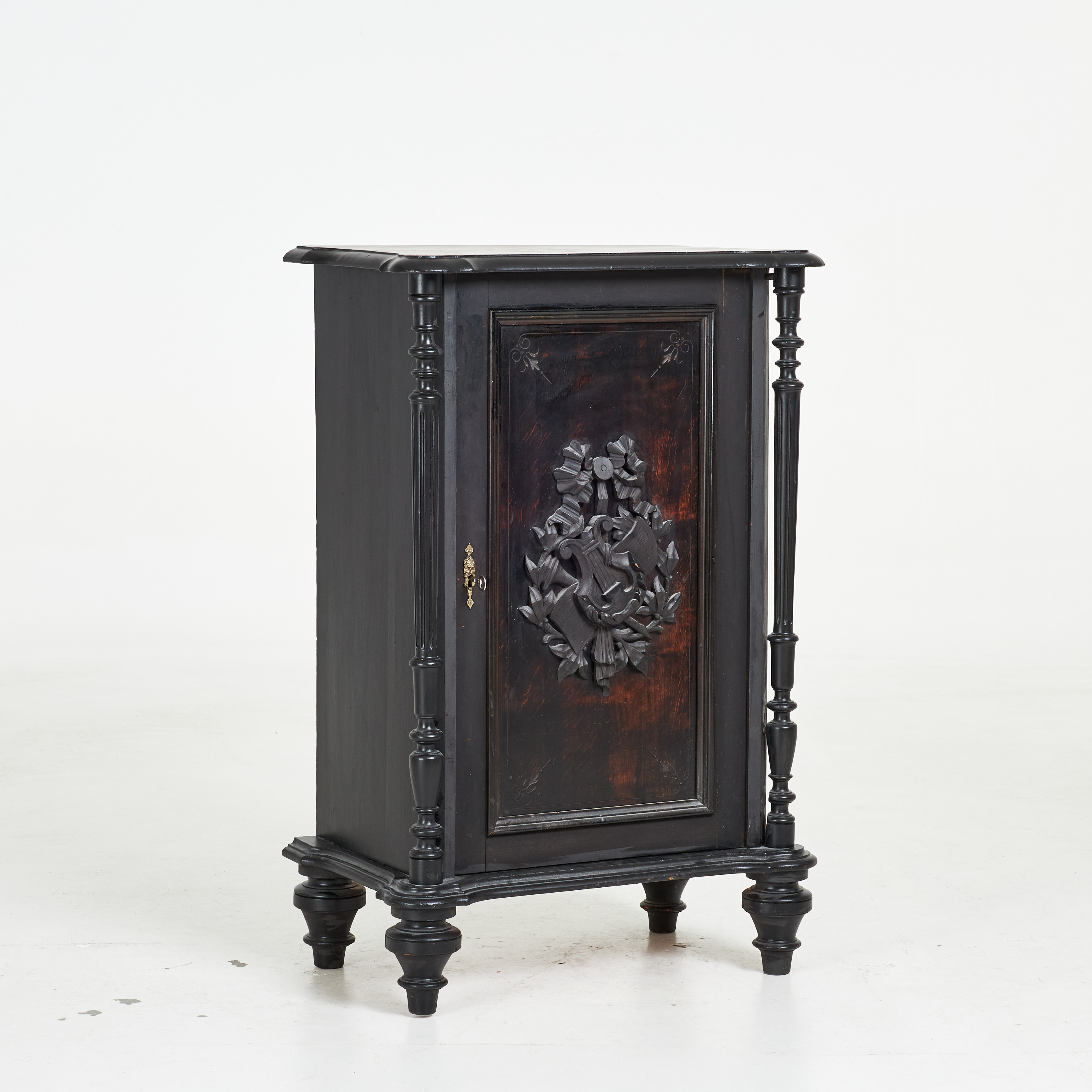 SKÅP/ NOTSKÅP, sekelskiftet 1800/1900, svartlackerad, reliefdekor med lyra och notblad.