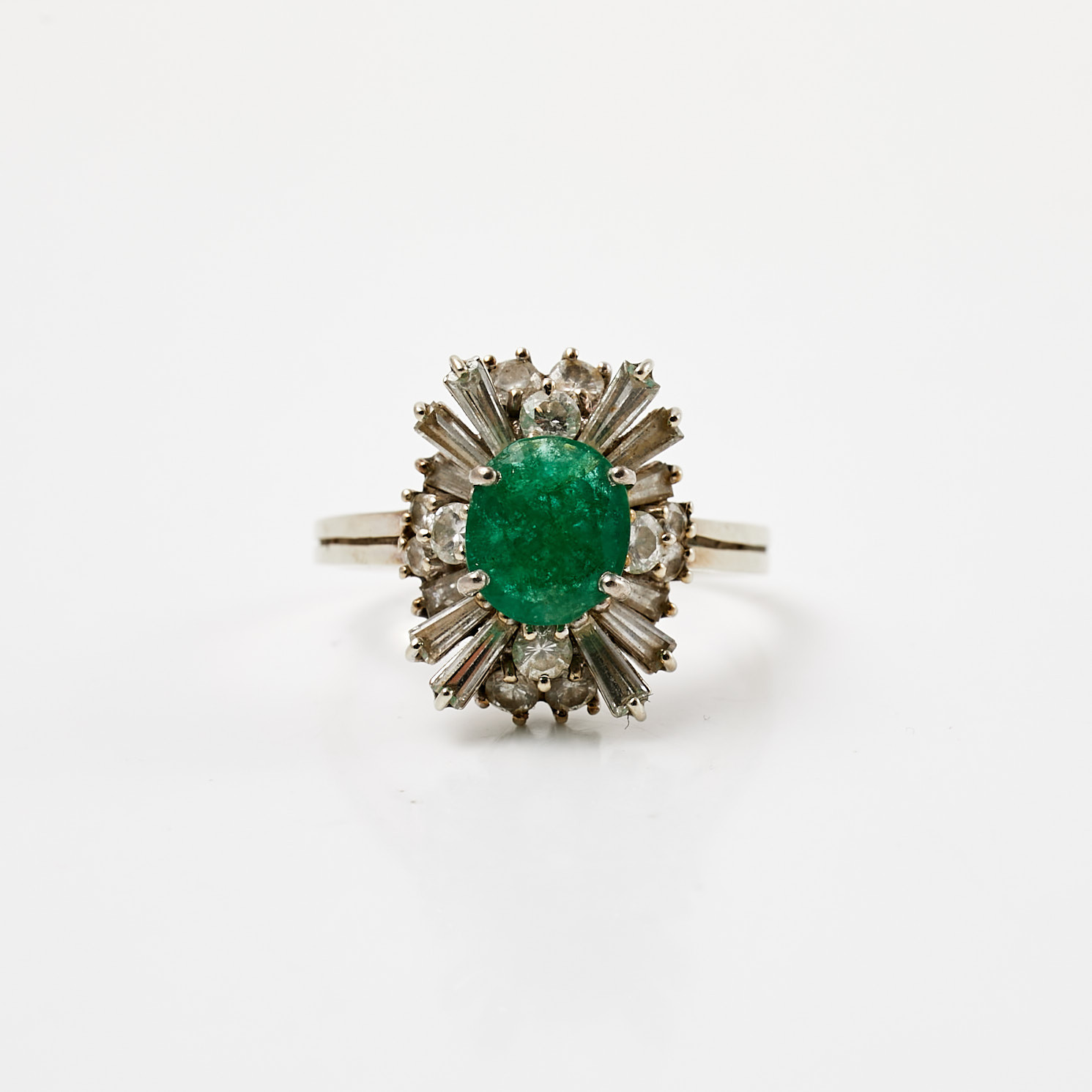 RING, 18 k vitguld, 1 ovalslipad smaragd, bekransad av diamanter med trapets- resp. briljantslipning, totalt ca 1,76 ct.