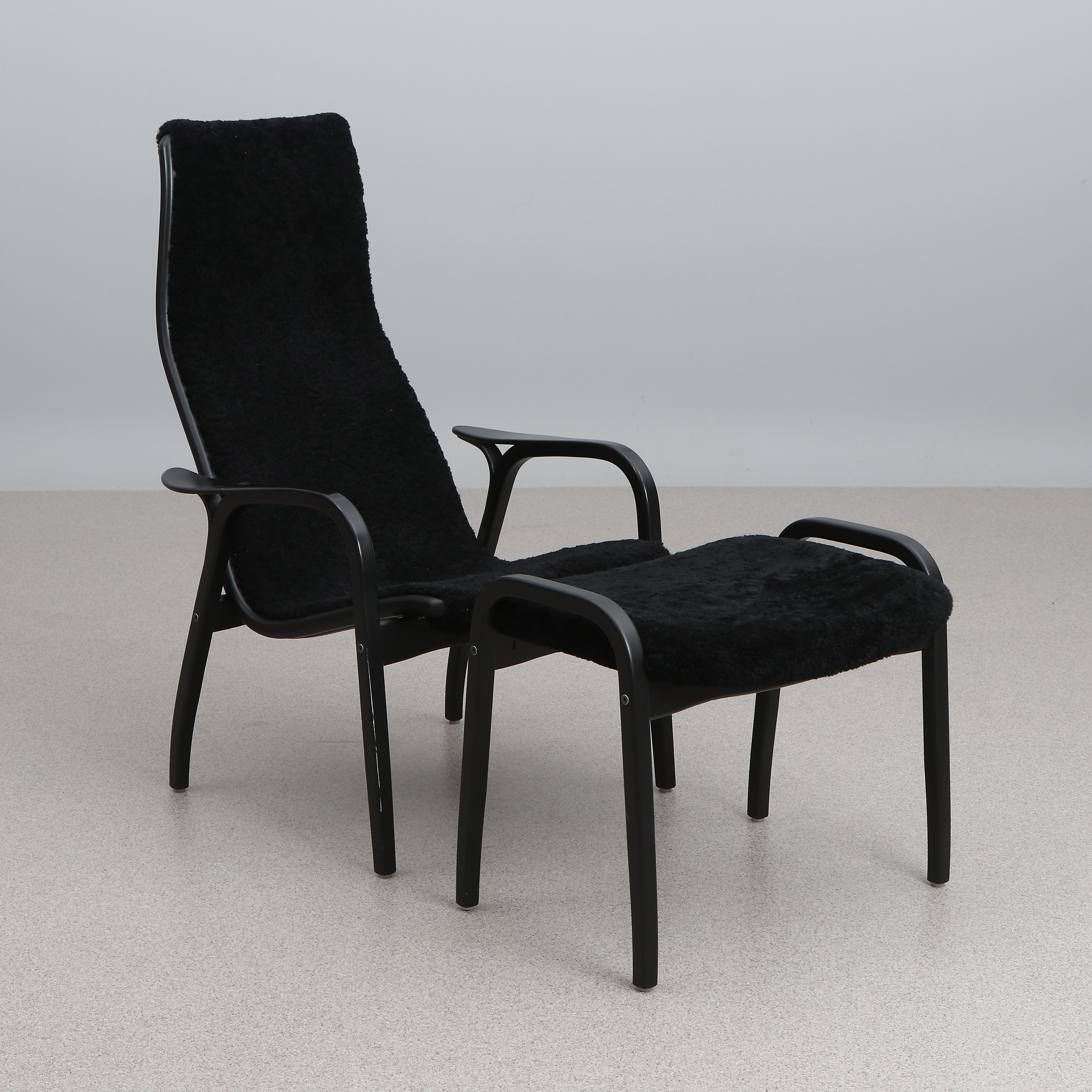 YNGVE EKSTRÖM. FÅTÖLJ MED FOTPALL. Lackerat trä med svart fårskinnsklädsel. "Lamino". Swedese. Tillverkad 2017, etikettmärkt undertill.