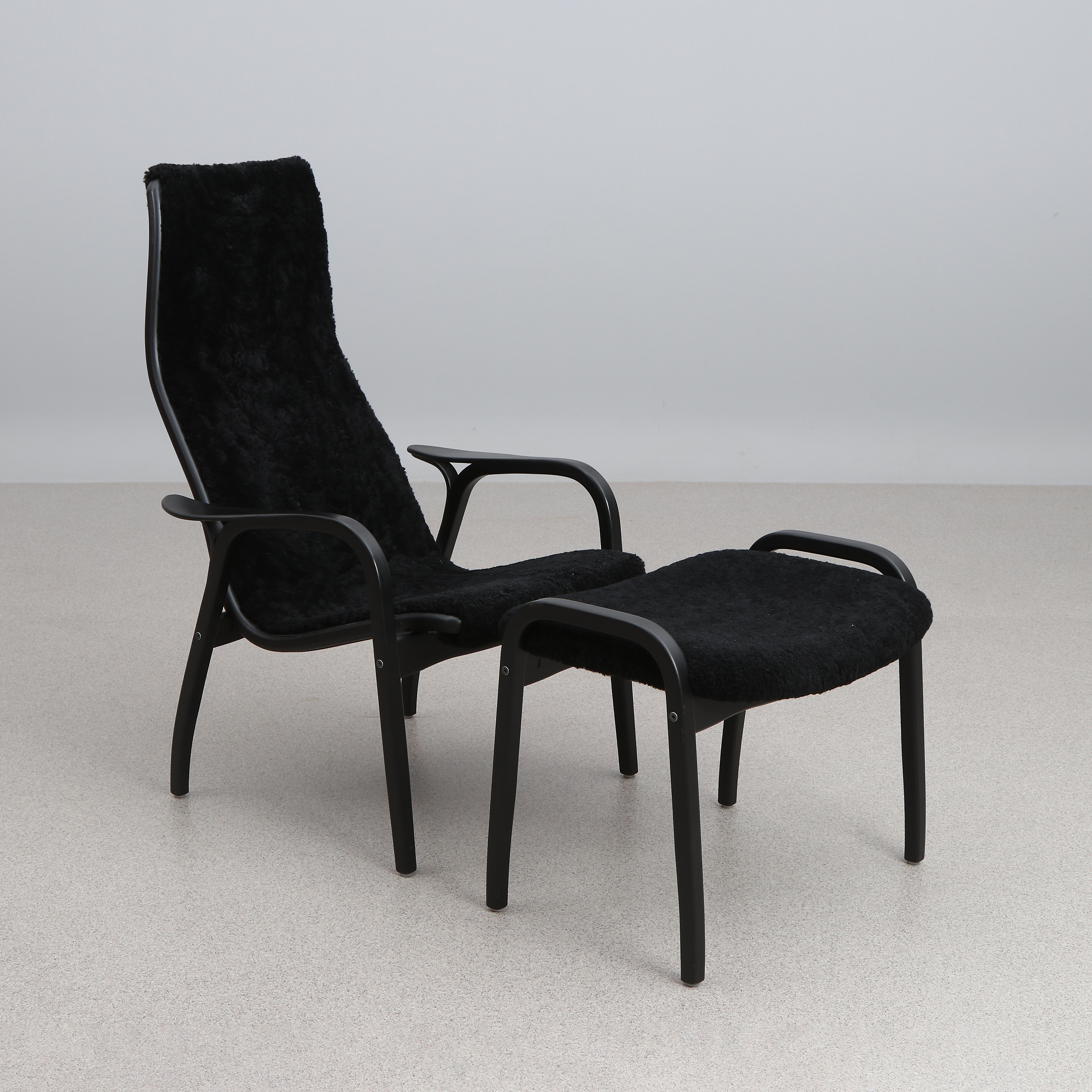 YNGVE EKSTRÖM. FÅTÖLJ MED FOTPALL. Lackerat trä med svart fårskinnsklädsel. "Lamino". Swedese. Tillverkad 2017, etikettmärkt undertill.