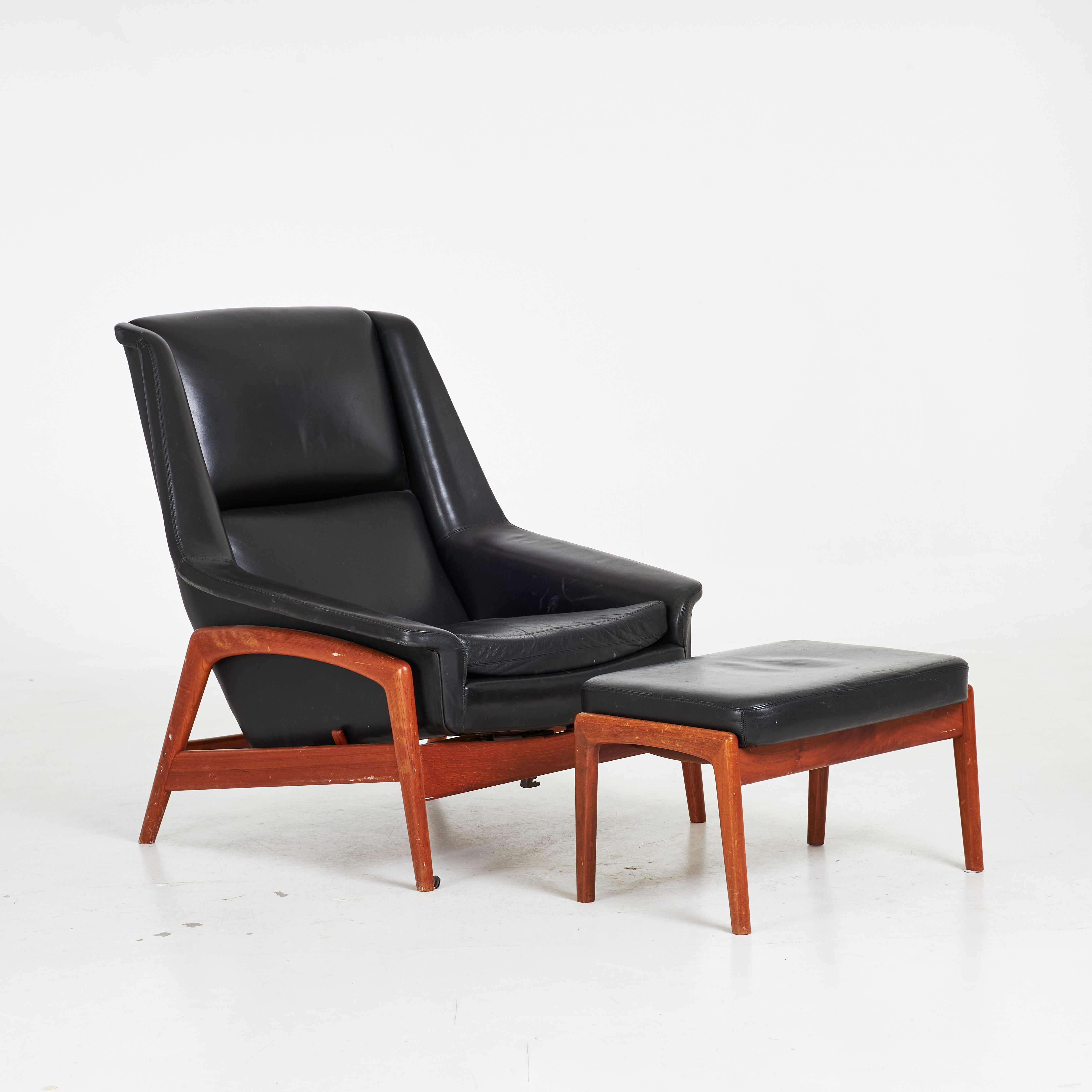 FOLKE OHLSSON. Fåtölj med fotpall, "Profil", Dux, 1950/60-tal, stomme i teak, helklädd i svart läder.