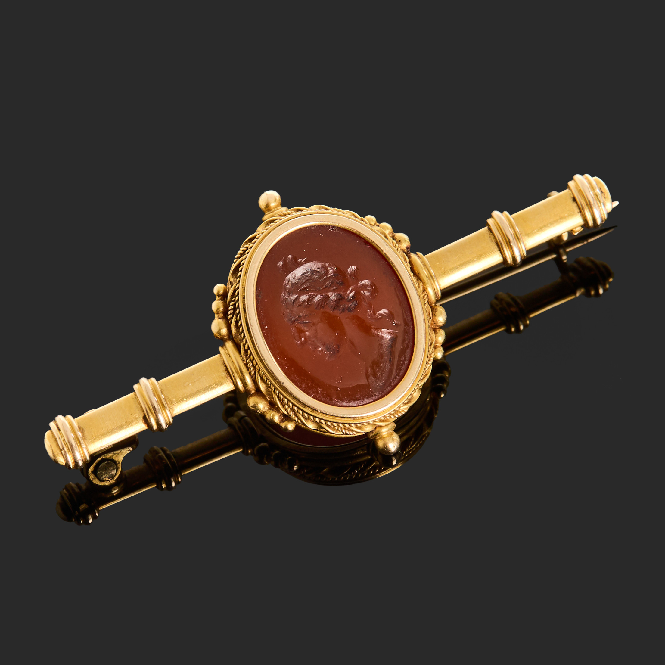 BROSCH, 18k guld dekorerat med en sardonyx med skuren dekor.