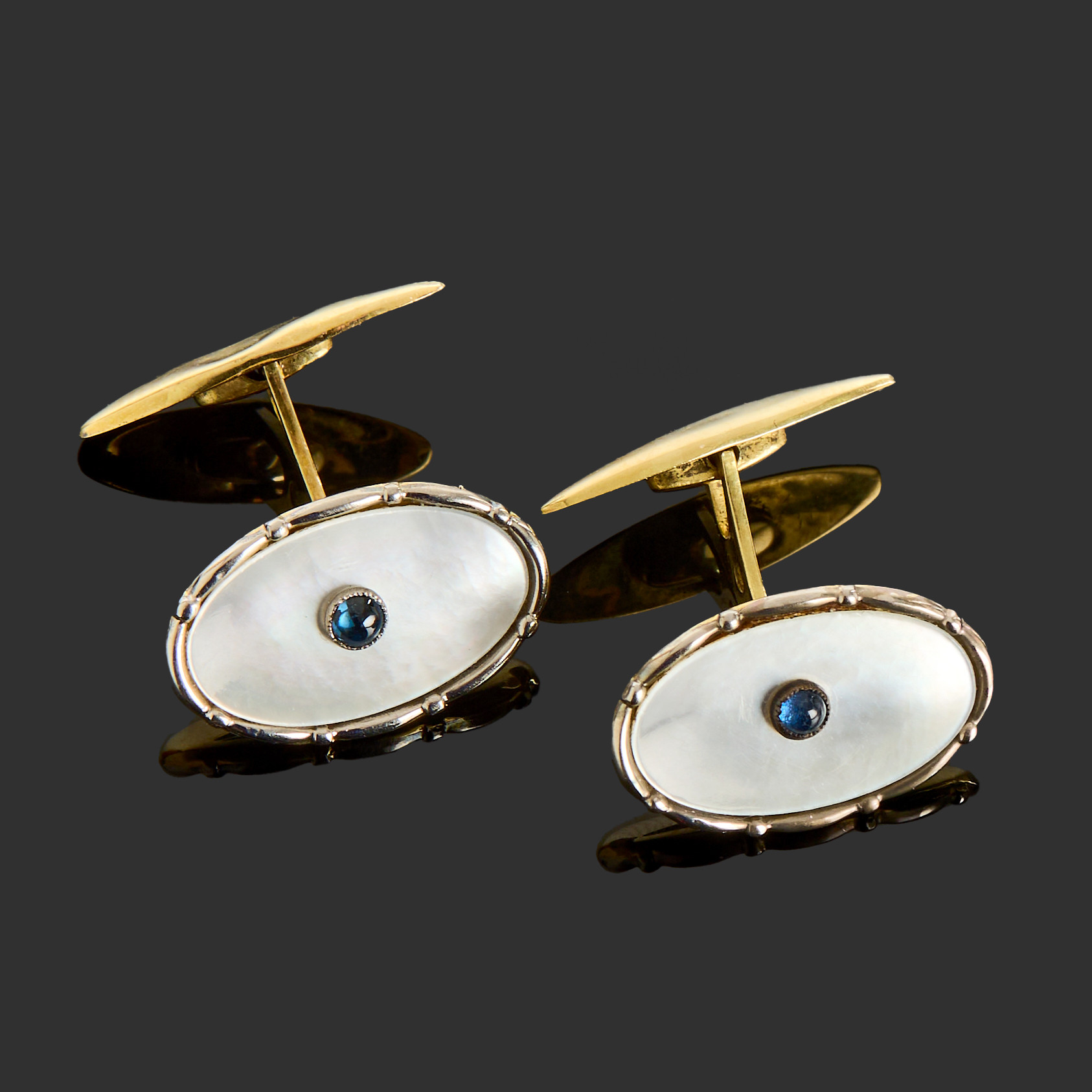 MANSCHETTKNAPPAR, 18k guld samt vitguld, pärlemor med en centrerad mörkblå cabochonslipad glassten.