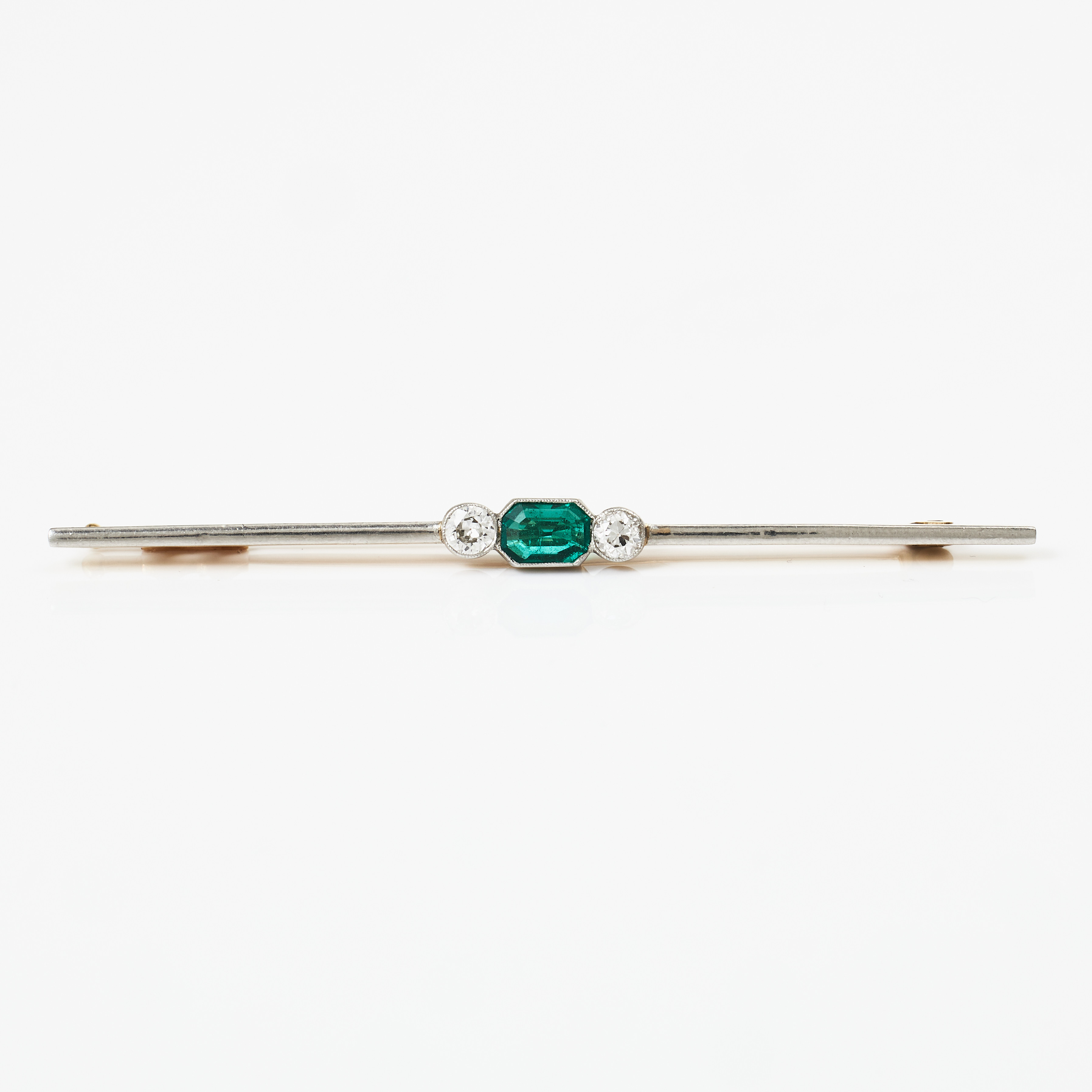 BROSCHNÅL, 18 k guld och platina, fantasislipad smaragd flankerad av 2 gammalslipade diamanter totalt ca 0,25 ct, C.G.Hallberg, Stockholm troligen 1919 (otdydligt årsindex).