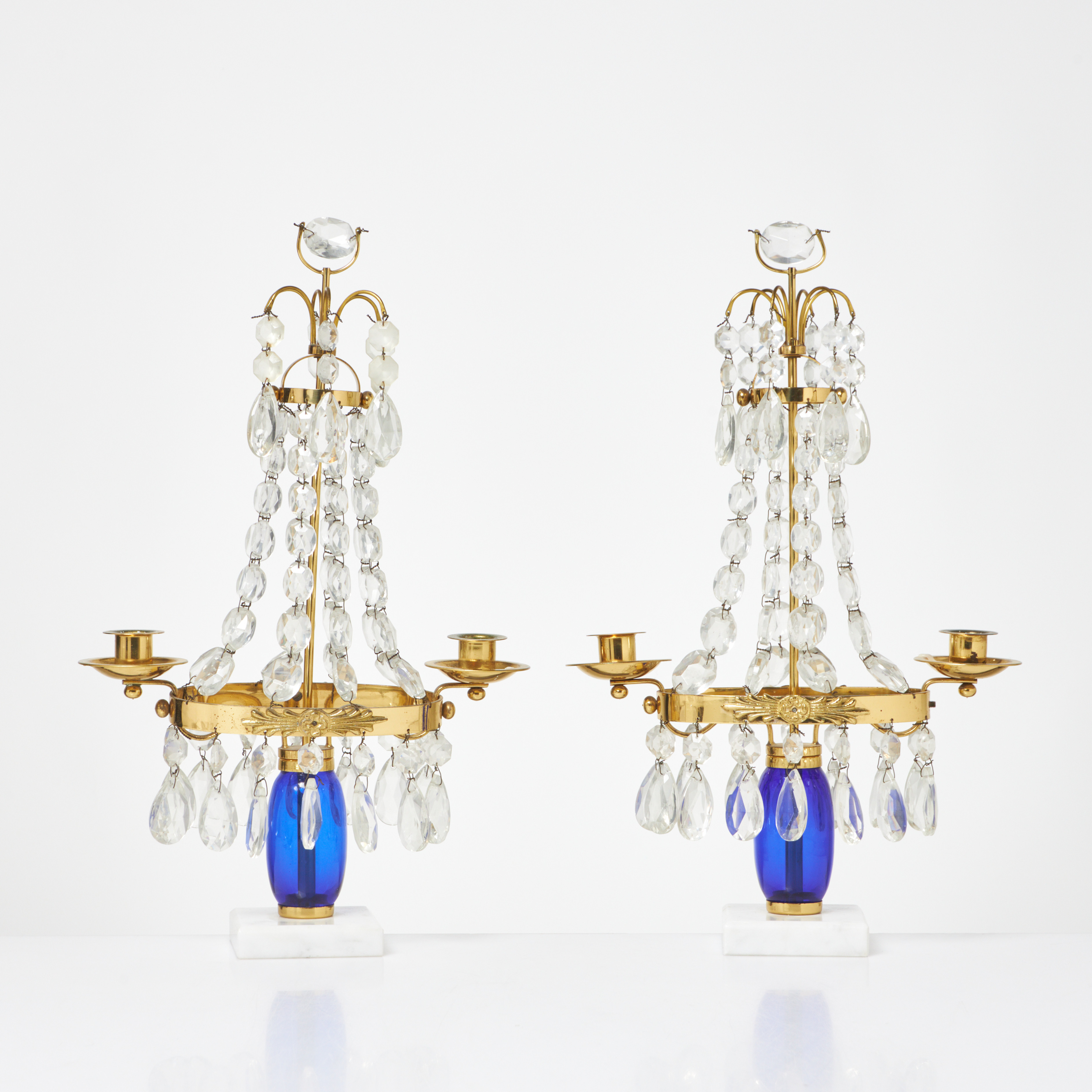 BORDSLYSTRAR. 1 par, 1900-tal, mässing, vardera två ljusarmar, behängda med olikslipade prismor i glas, socklar i sten.