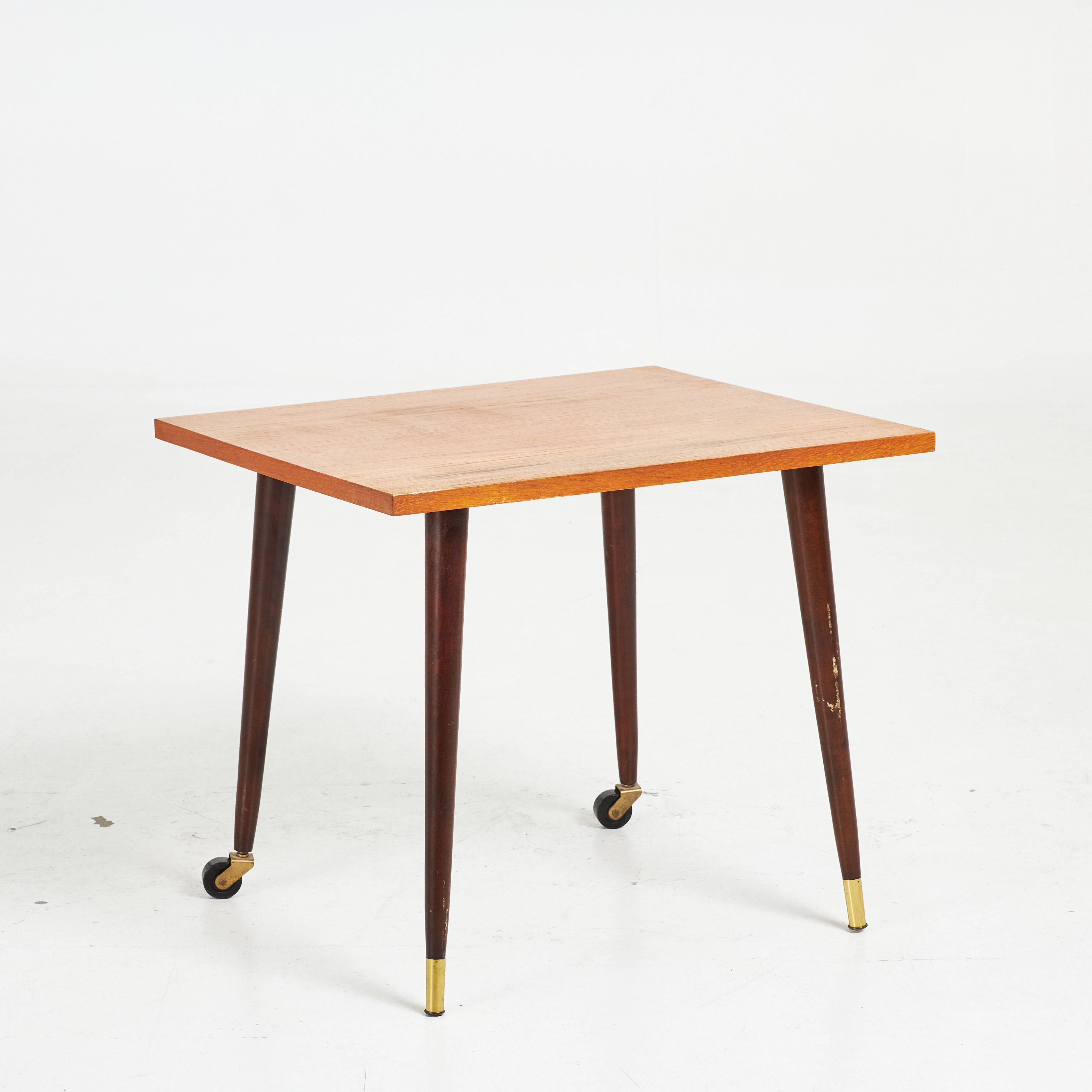 SIDOBORD, 1900-talets mitt, skiva fanerad i teak, betsade ben med hjul samt mässingsavslut.