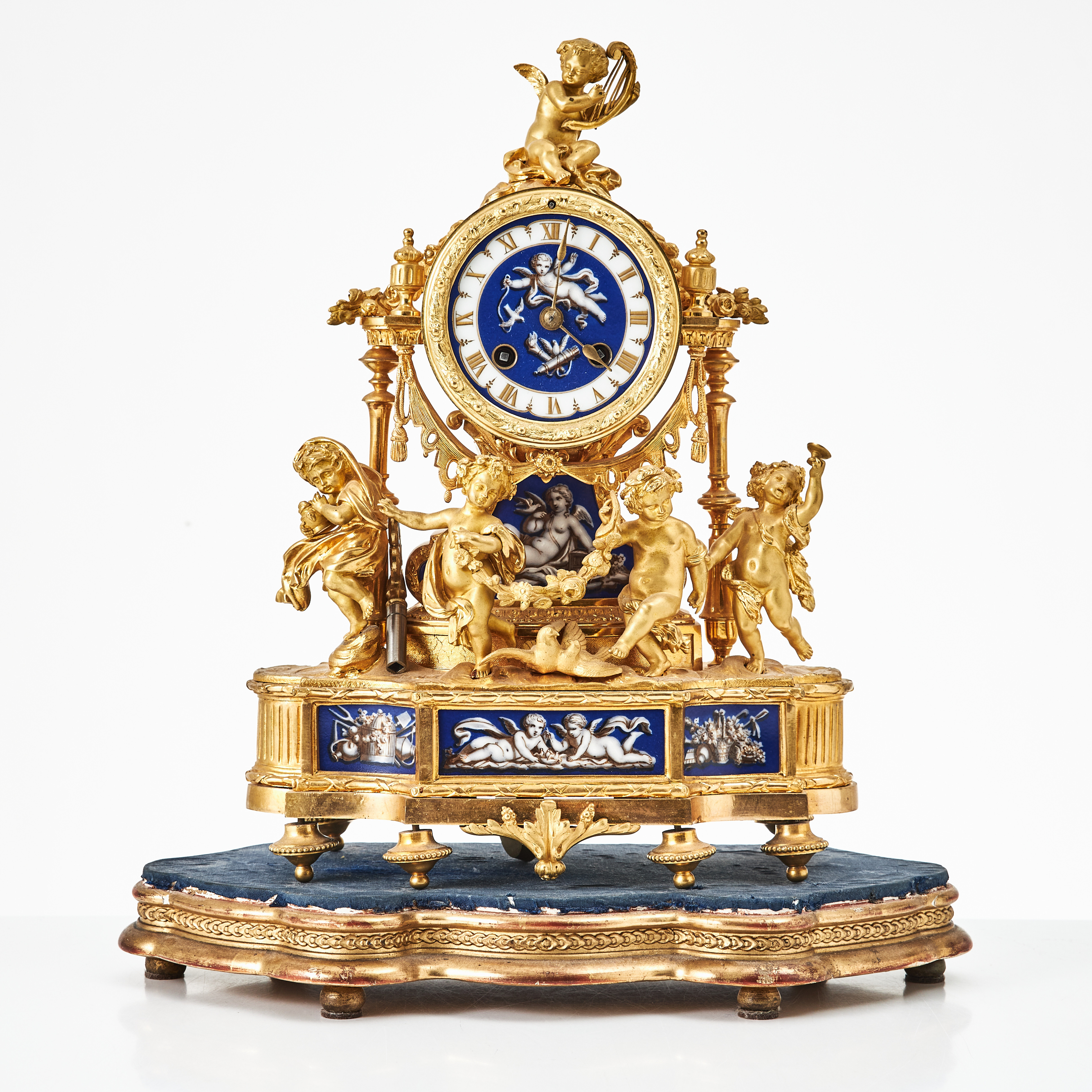 BORDSPENDYL, 1800-talets mitt, Louis XVI stil, förgylld brons, emaljerad urtavla, dekor av puttis, porslinsplacketter.