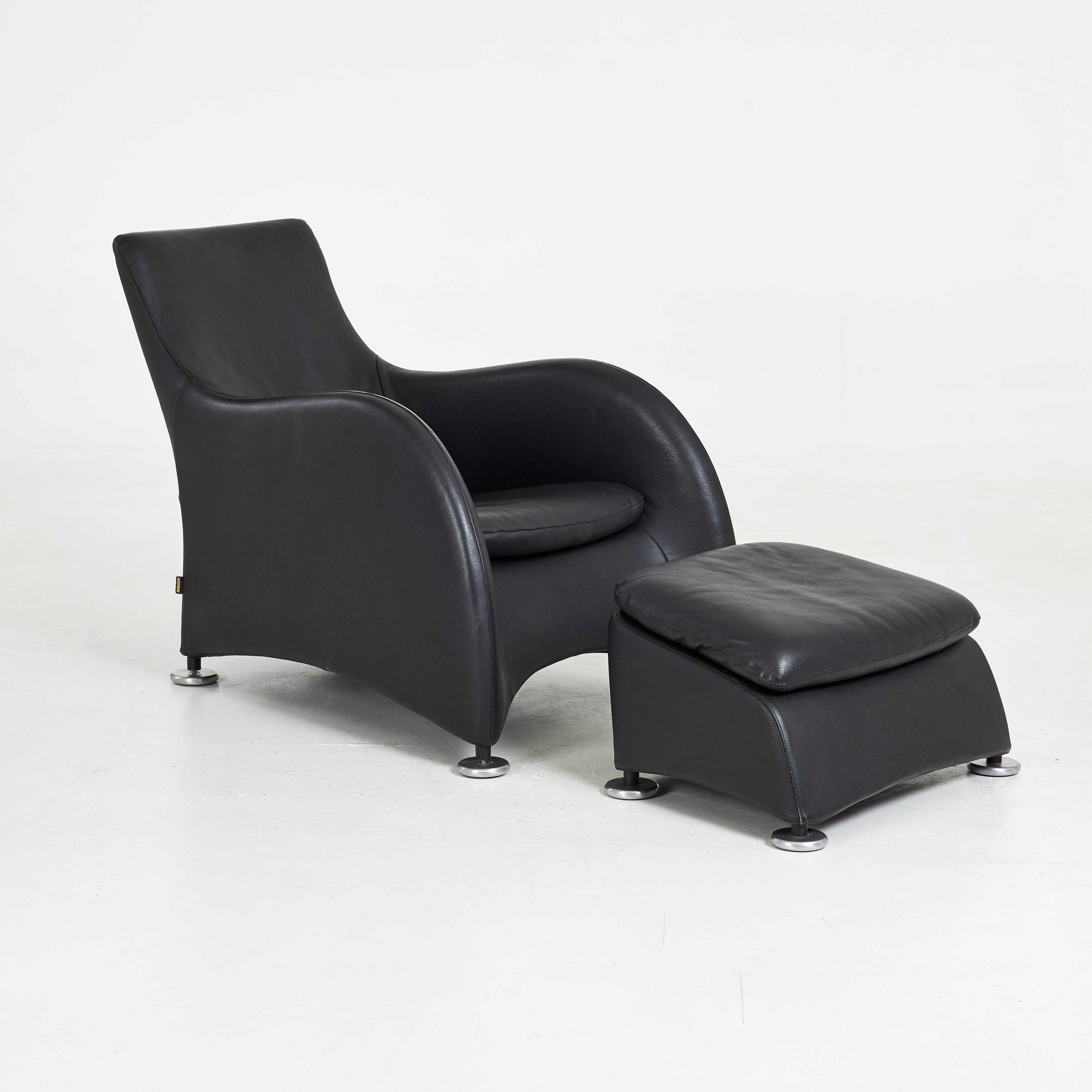 GERARD VAN DEN BERG. Fåtölj med fotpall, 2 dlr, "Loge", klädsel i svart läder, etikettmärkt Montis, Nederländerna.