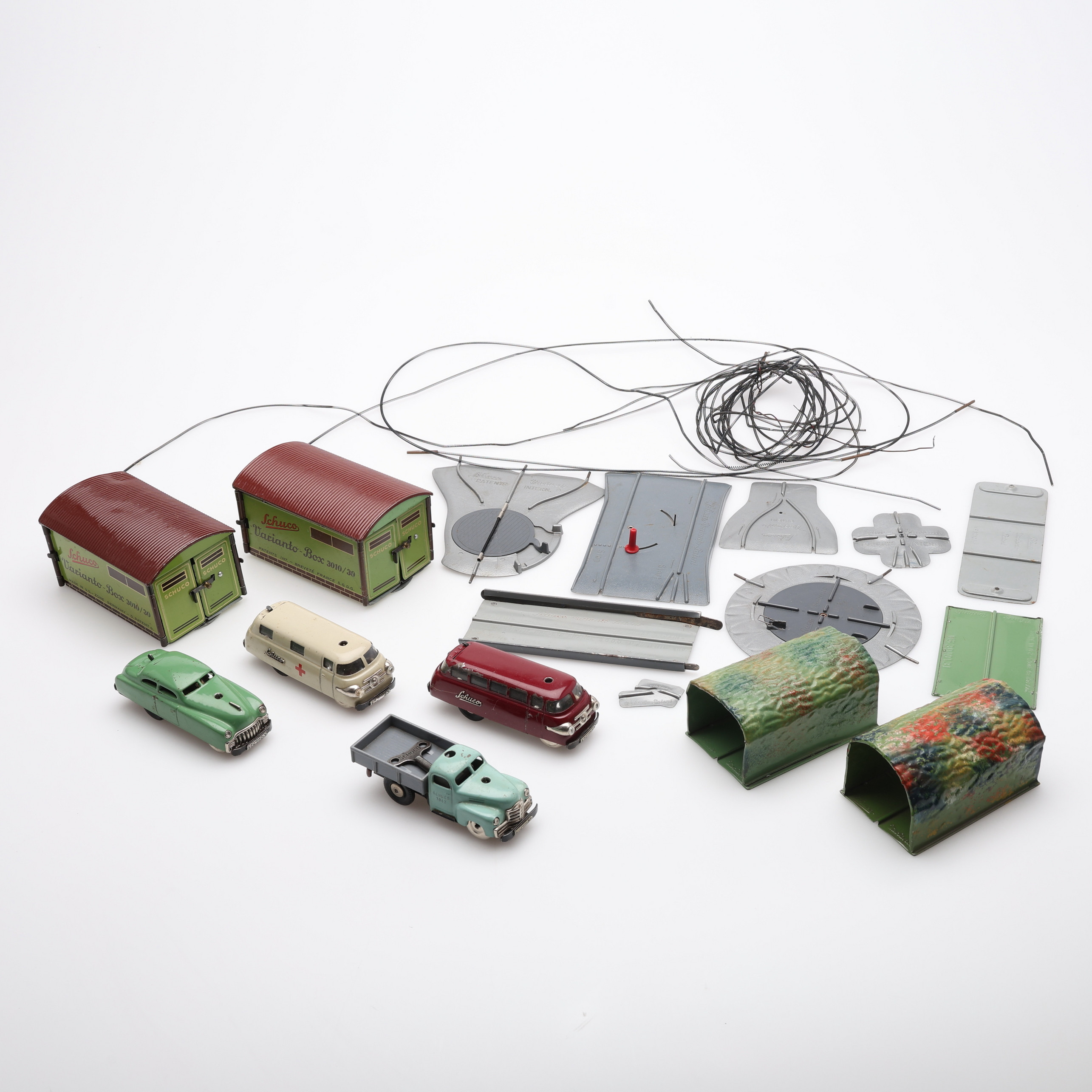 DELAR TILL SCHUCO VARIANTO-BILBANA 3110. 4 bilar, 2 garage, 2 tunnlar samt diverse skenor och spiraler. 1950-tal.