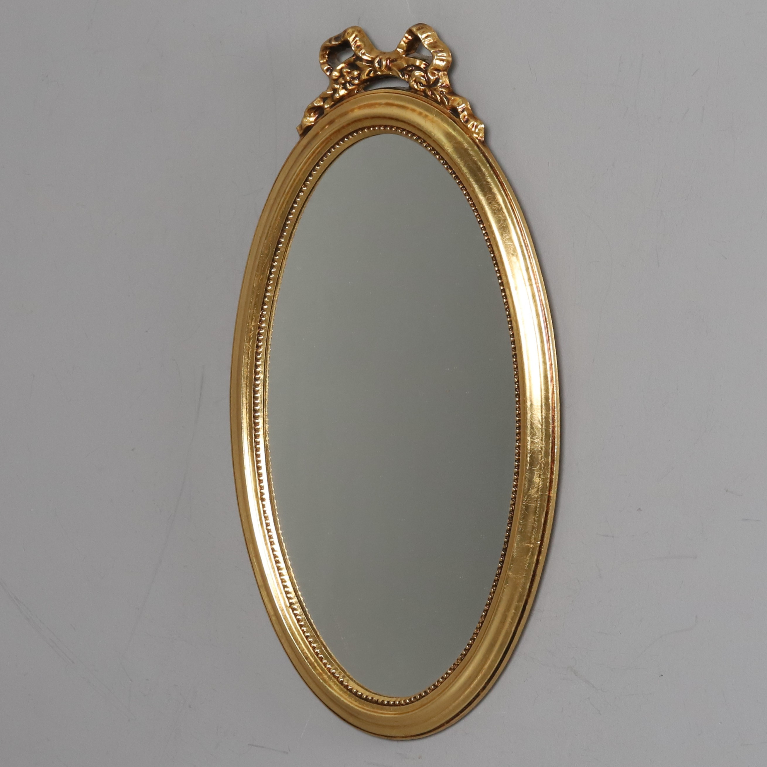 SPEGEL. Förgyllt trä, oval med pärlkant och topprosett, 1900-talets mitt.