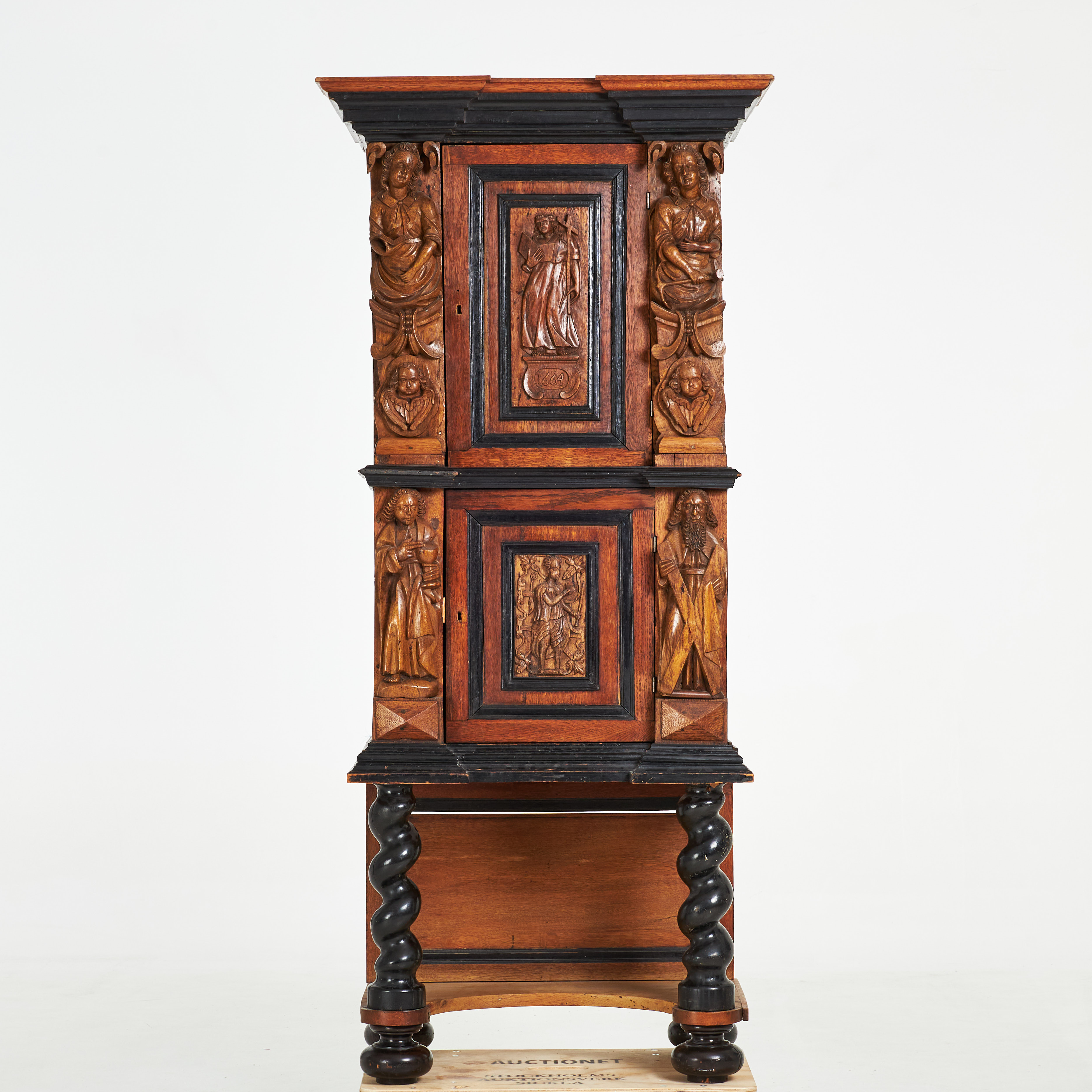 SKÅP. Barock, 1600 tal, speglar med rikligt skuren dekor i ek, bär äret 1664, svärtade detaljer, spiralskuret underrede, klotfötter.