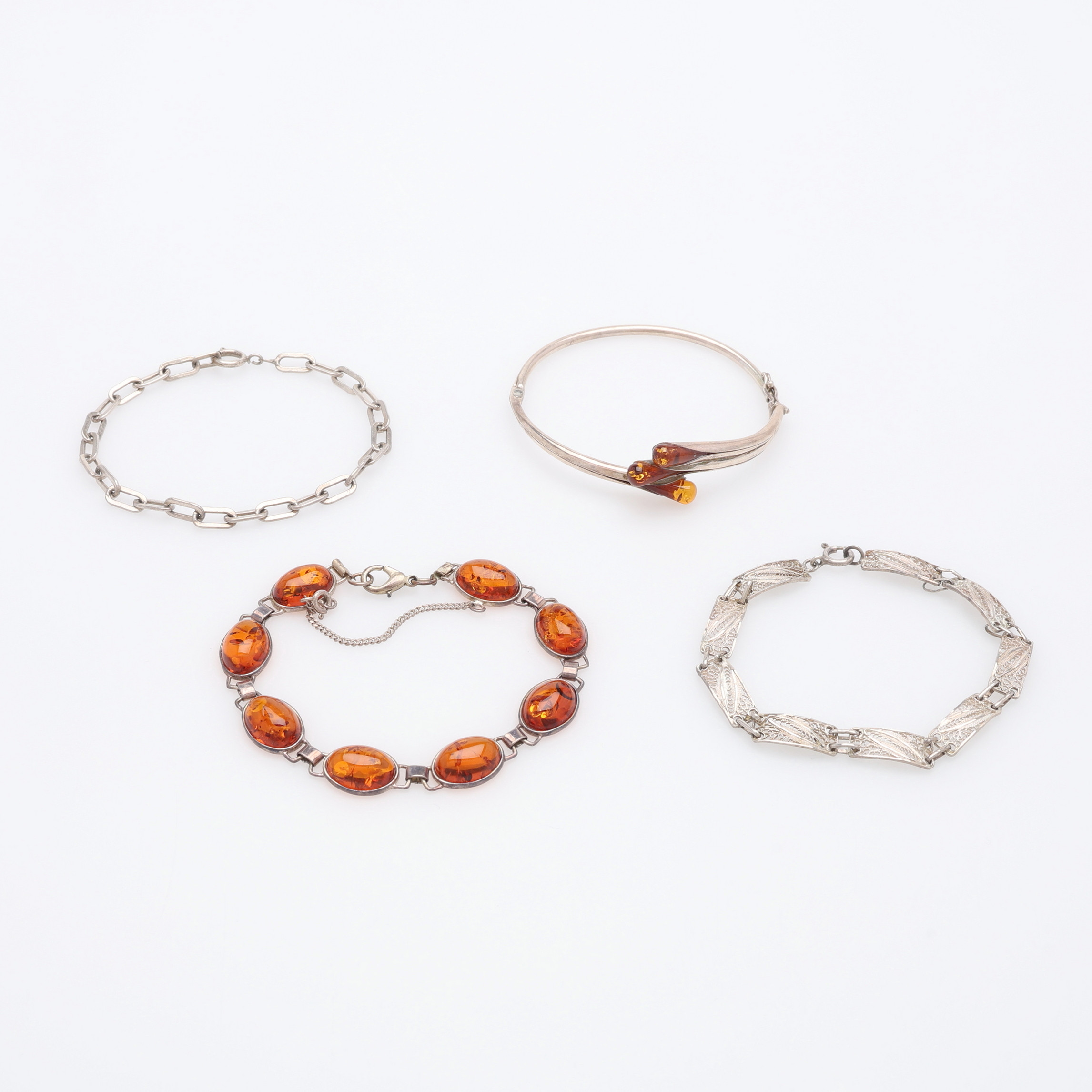ARMBAND, SILVER OCH BÄRNSTEN, FYRA STYCKEN.