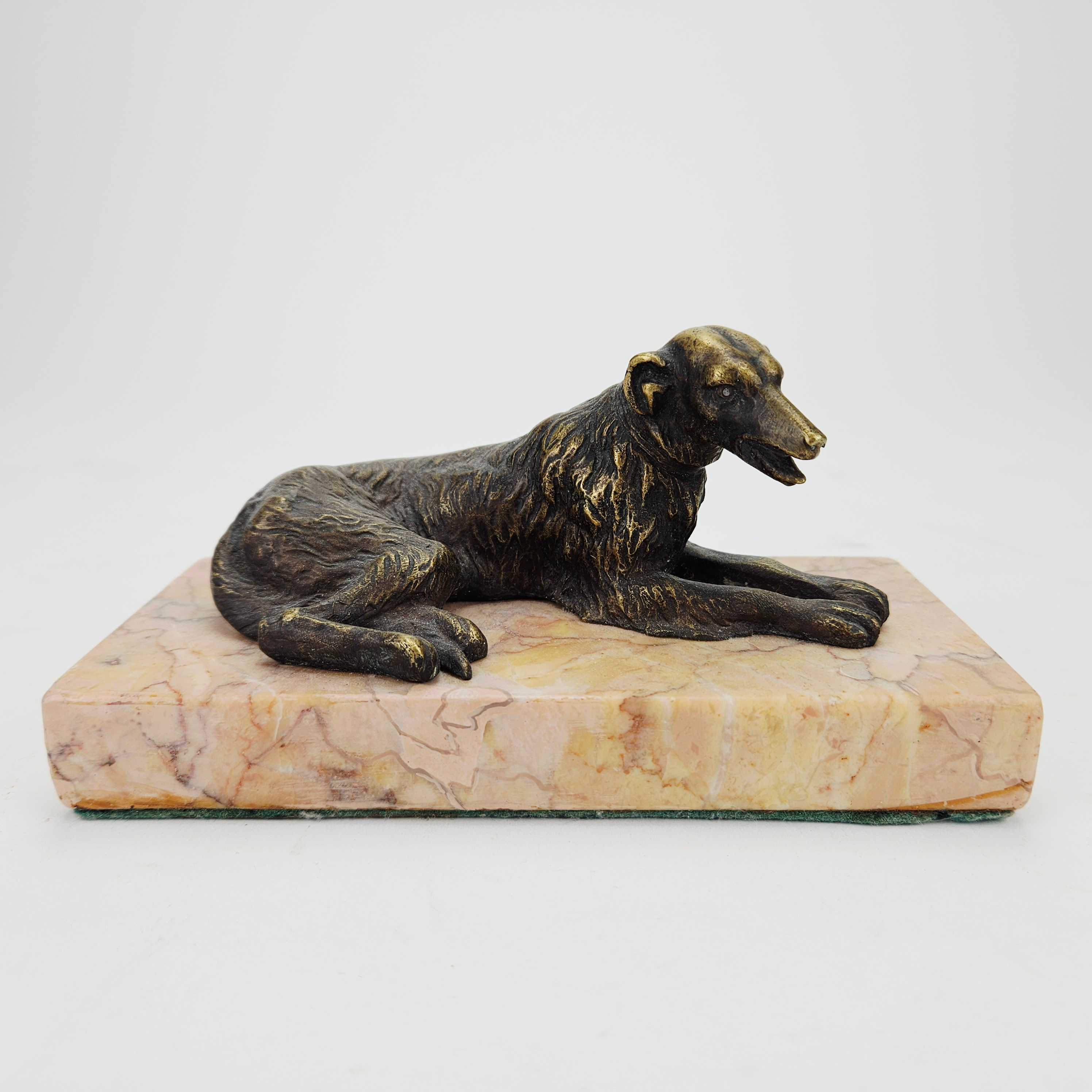 BREVPRESS, bronspatinerad metall, stensockel, i form av liggande Borzoi, 1900-tal.