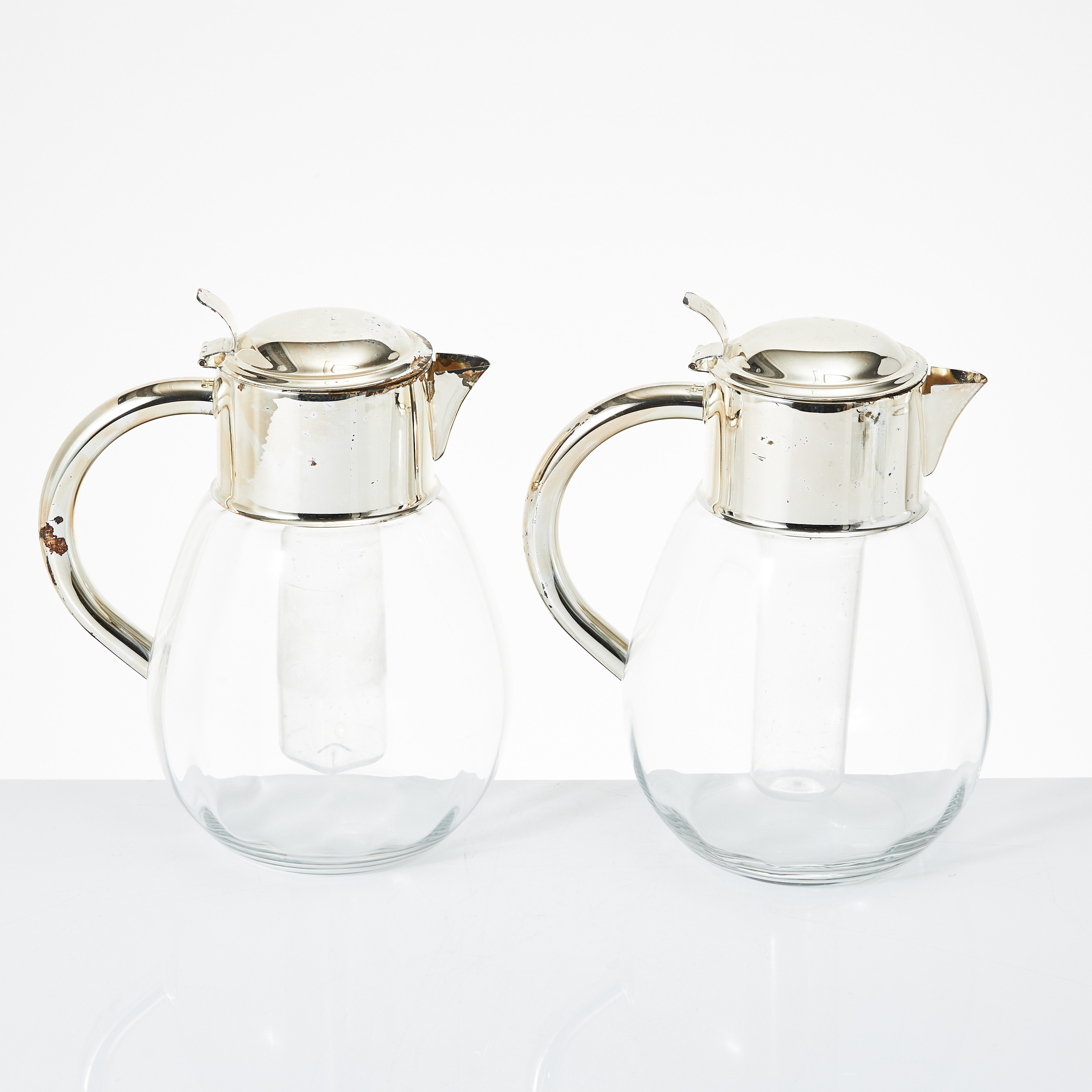 TILLBRINGARE, 2 stycken, 1990-tal, glas med beslag av nysilver. Köpta på Firma Svenskt Tenn.