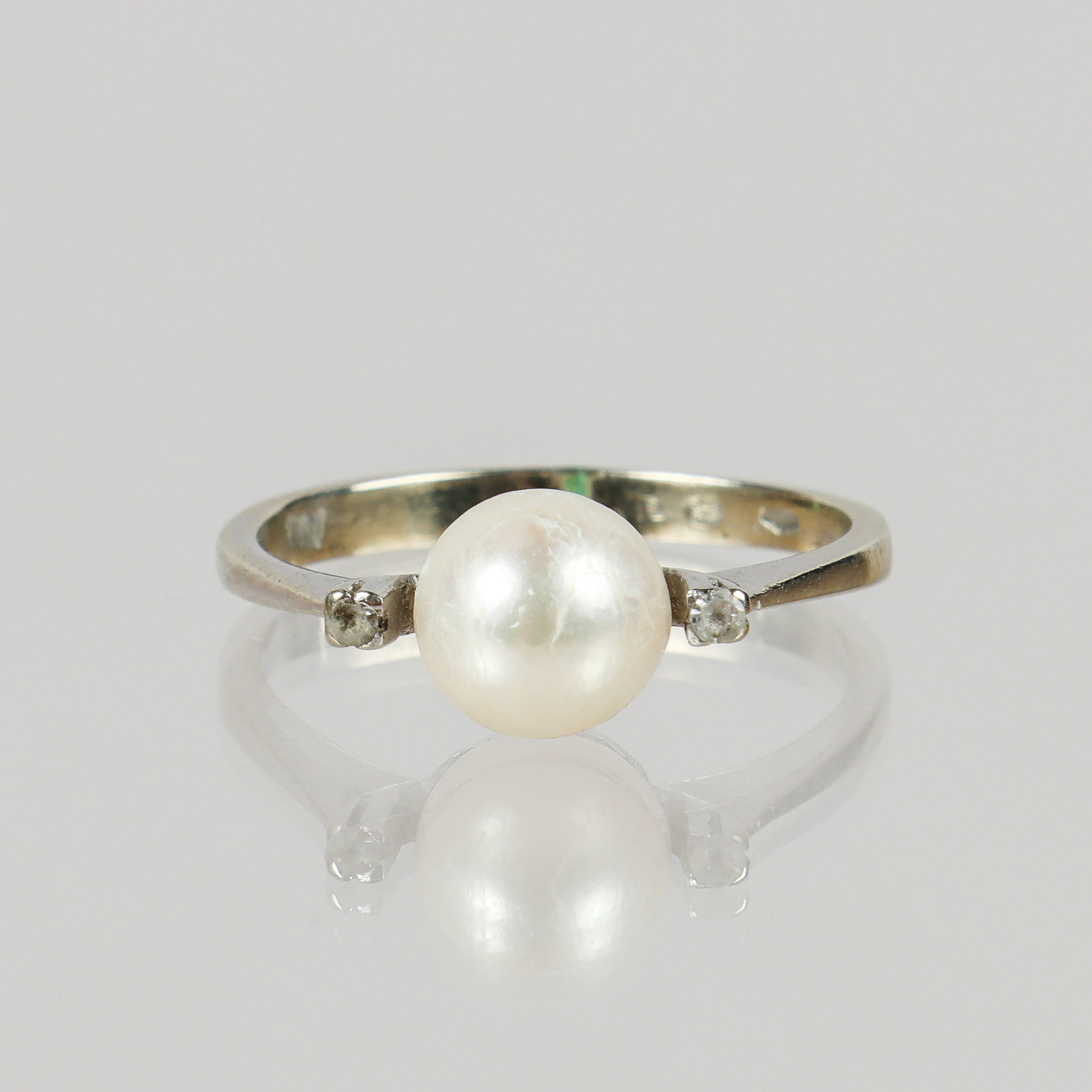 RING 18k vitguld med odlad pärla och 2 vita stenar.
