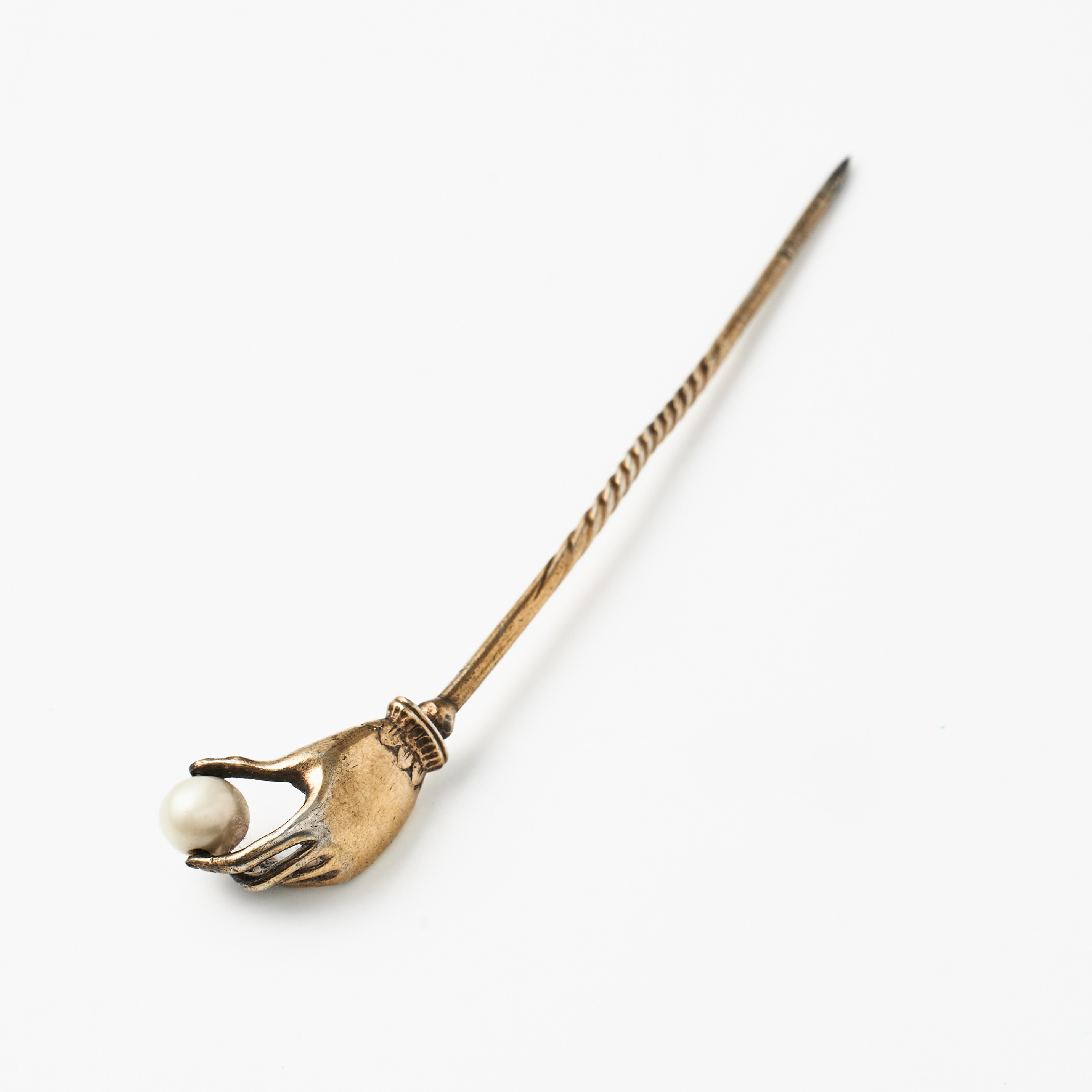KRAVATTNÅL, förgyllt troligen silver, 1800-talets andra hälft, föreställande en hand hållandes en flodpärla.