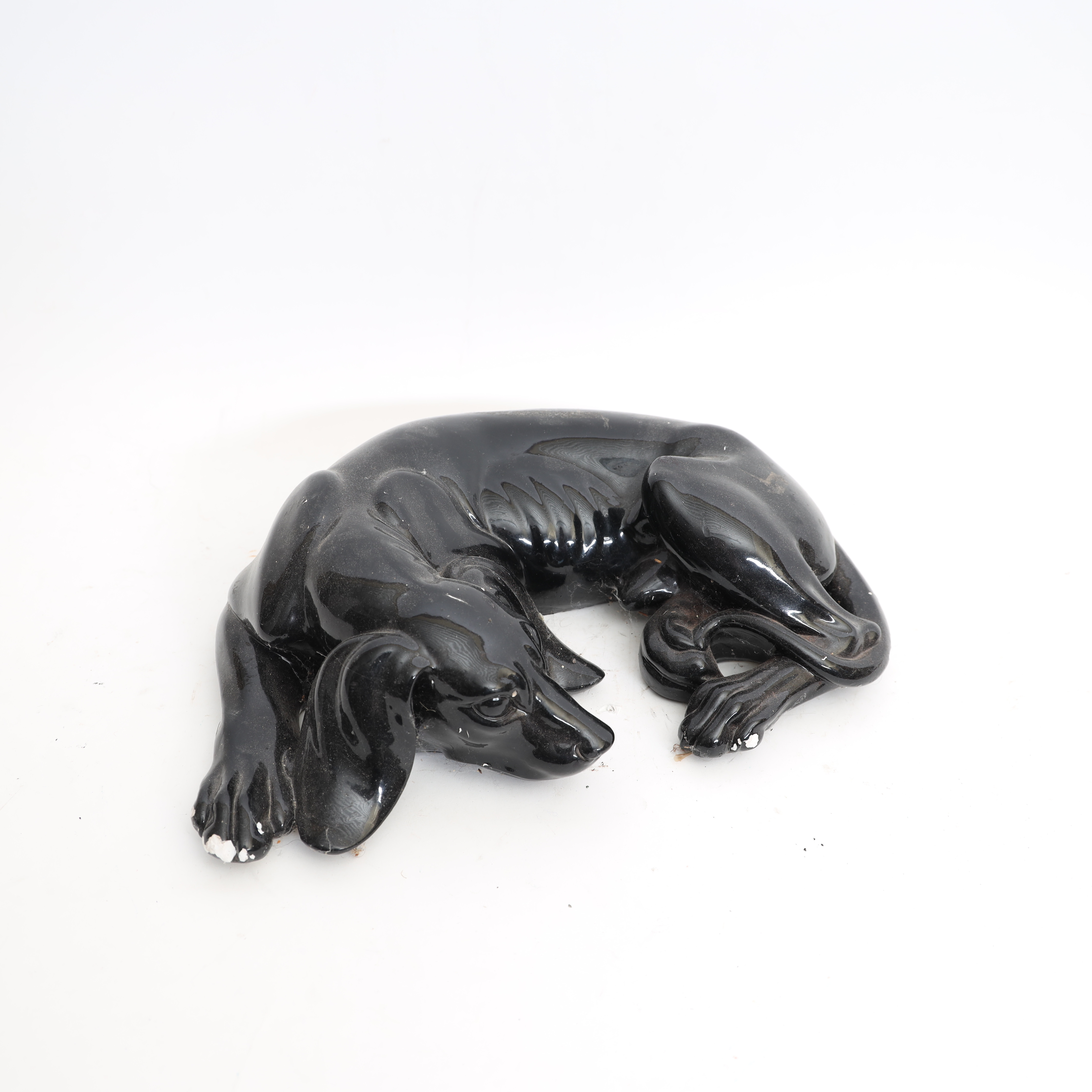 SKULPTUR, 1900-talets andra hälft, föreställande vilande hund, bemålad gips.