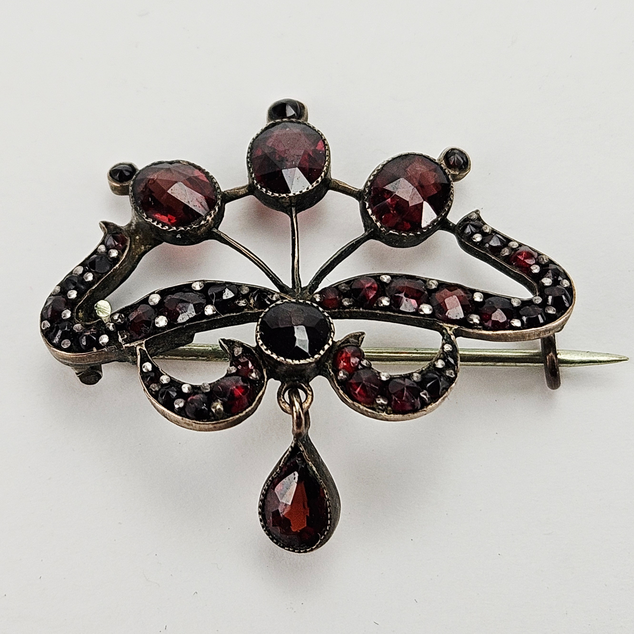 BROSCH, metall, med röda slipade stenar, sannolikt granater, 1900-tal.