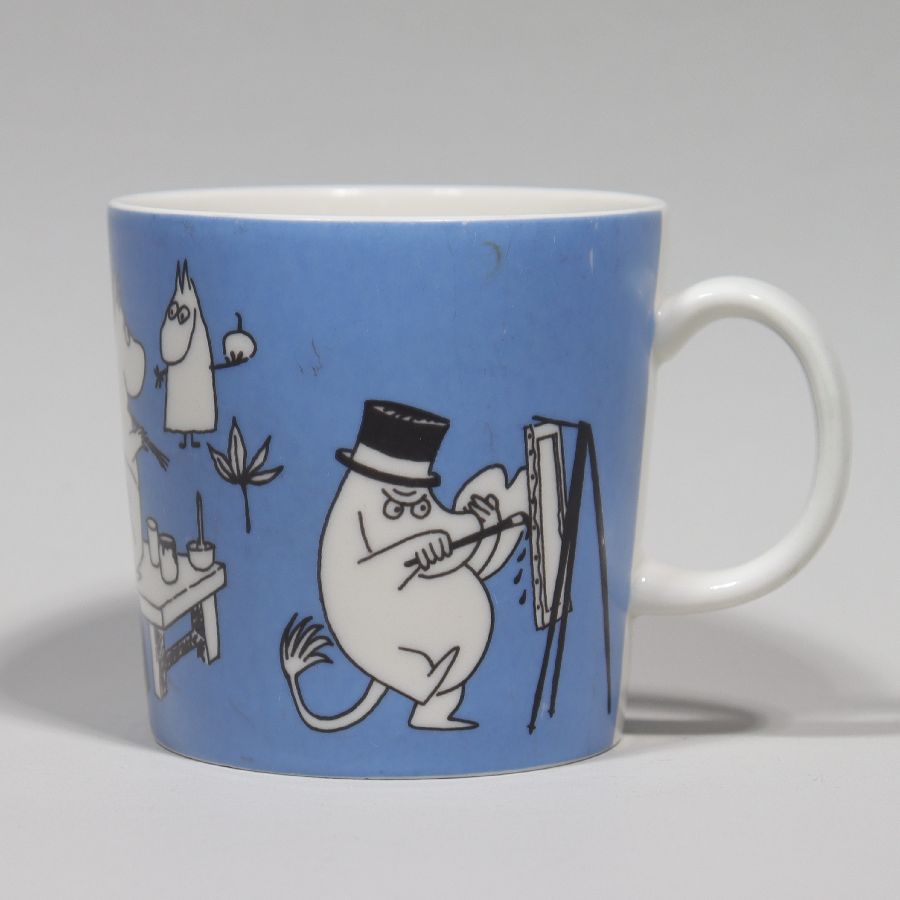 MUMINMUGG, "Mugg Blå, Målande Mumin", Teema stämplad, Arabia, 1990-1996.