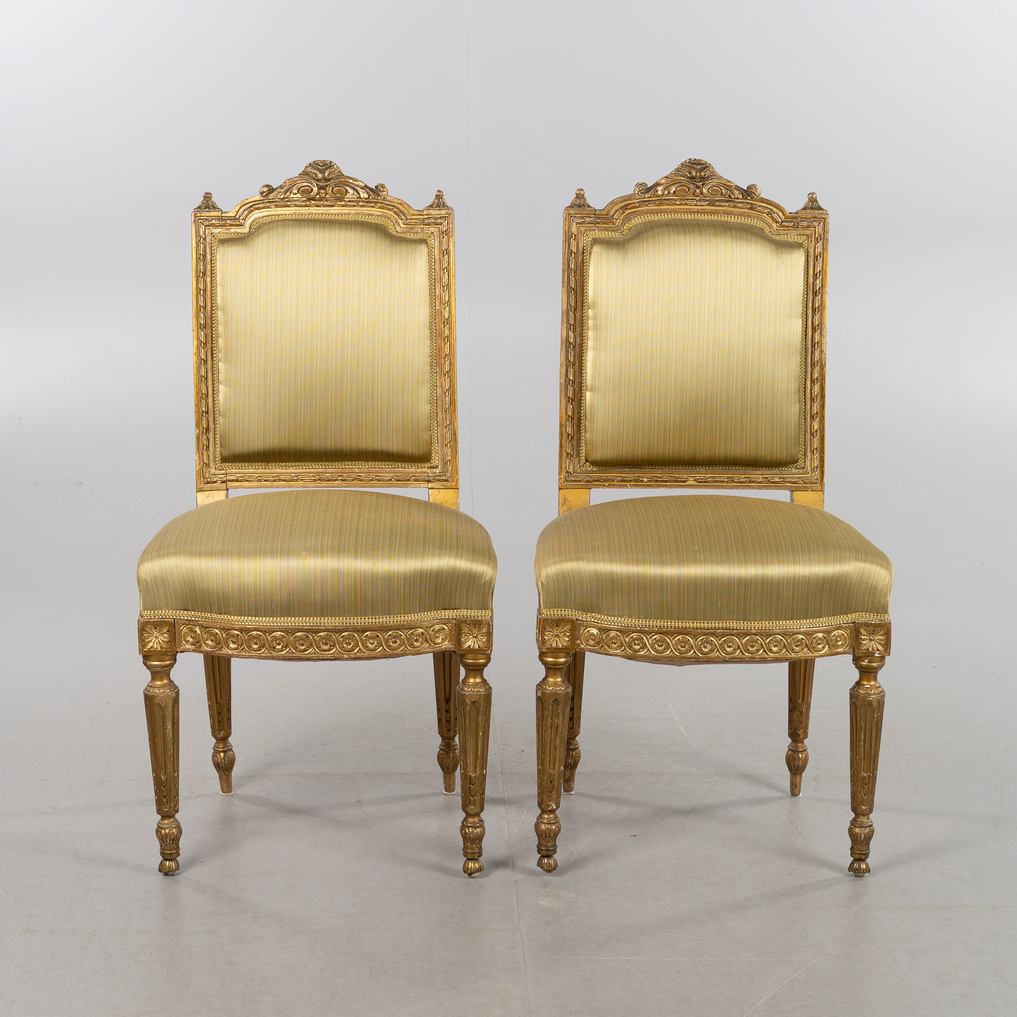 STOLAR, 1 par, Louis XVI-stil, omkring år 1900, bronserade och förgyllda stommar, fast stoppade sitsar och ryggar klädda med tyg.